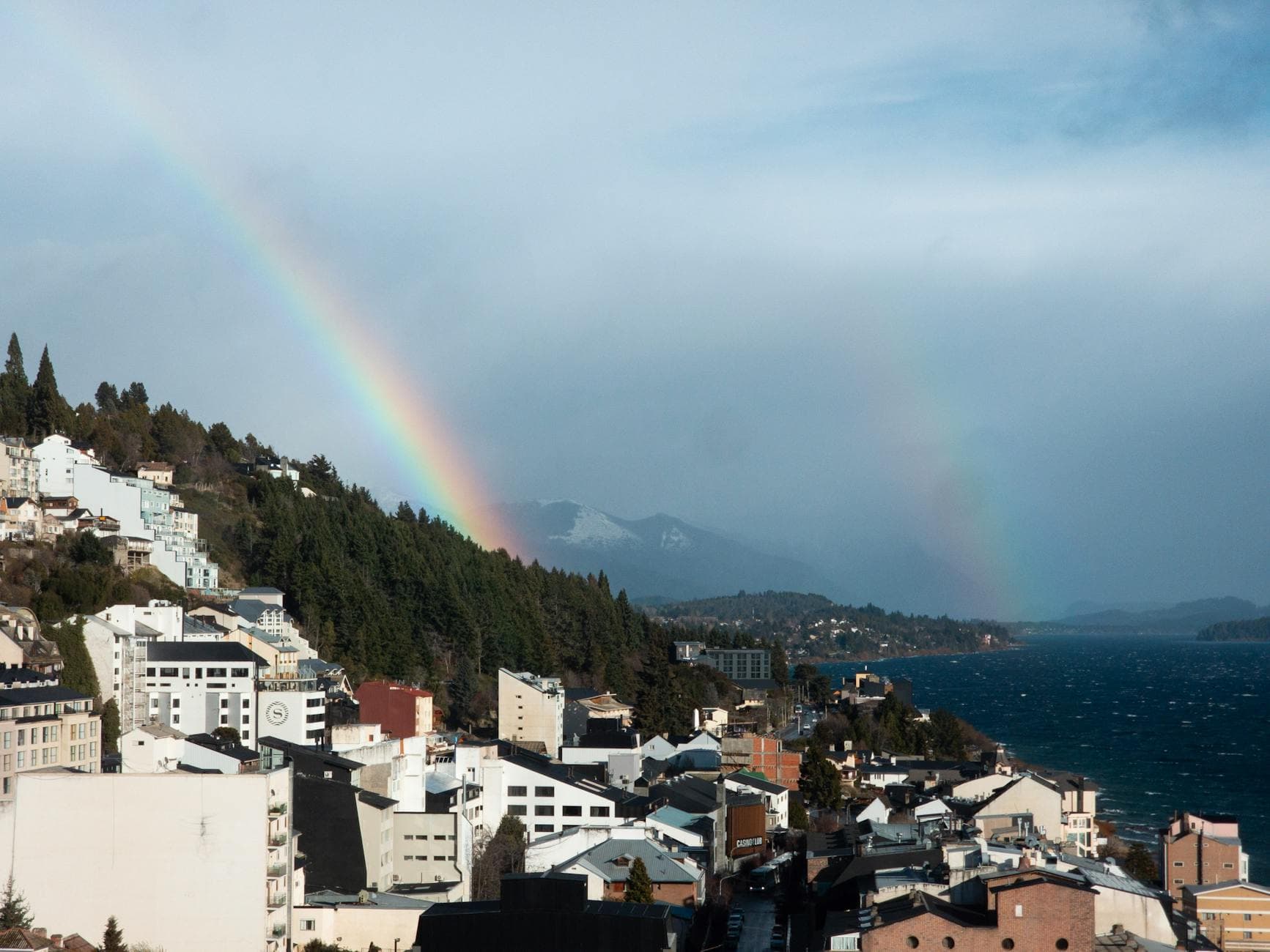 A vibrant rainbow graces the skies over San Carlos de Bariloche, offering a breathtaking view of Patagonia's Andes mountains.