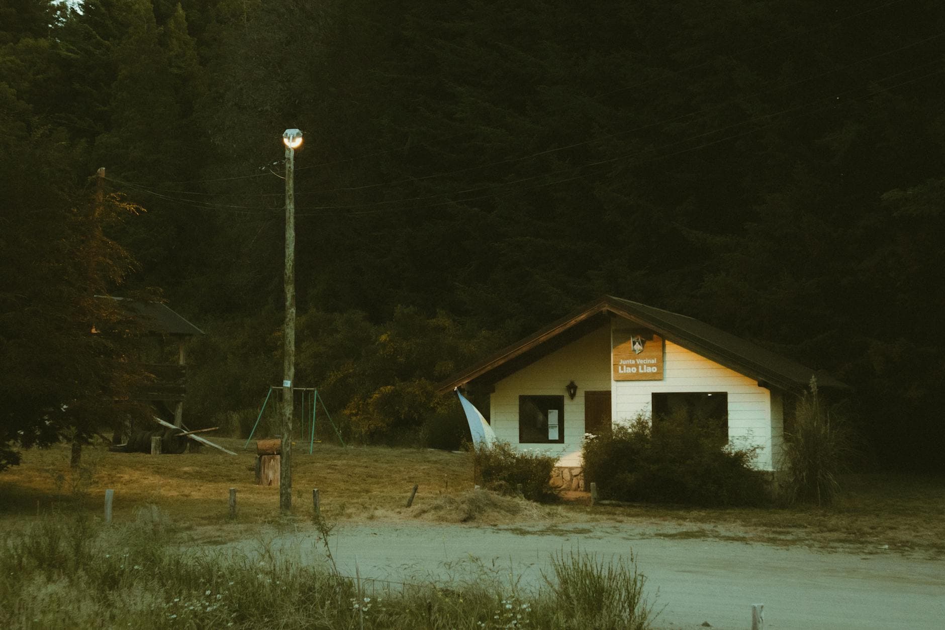 A rustic cabin and street lamp glow softly in the Bariloche countryside, Argentina.
