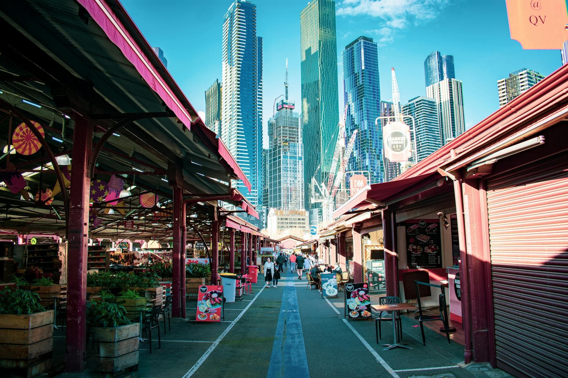 Explore the vibrant atmosphere of Queen Victoria Market with Melbourne's skyline as a backdrop.