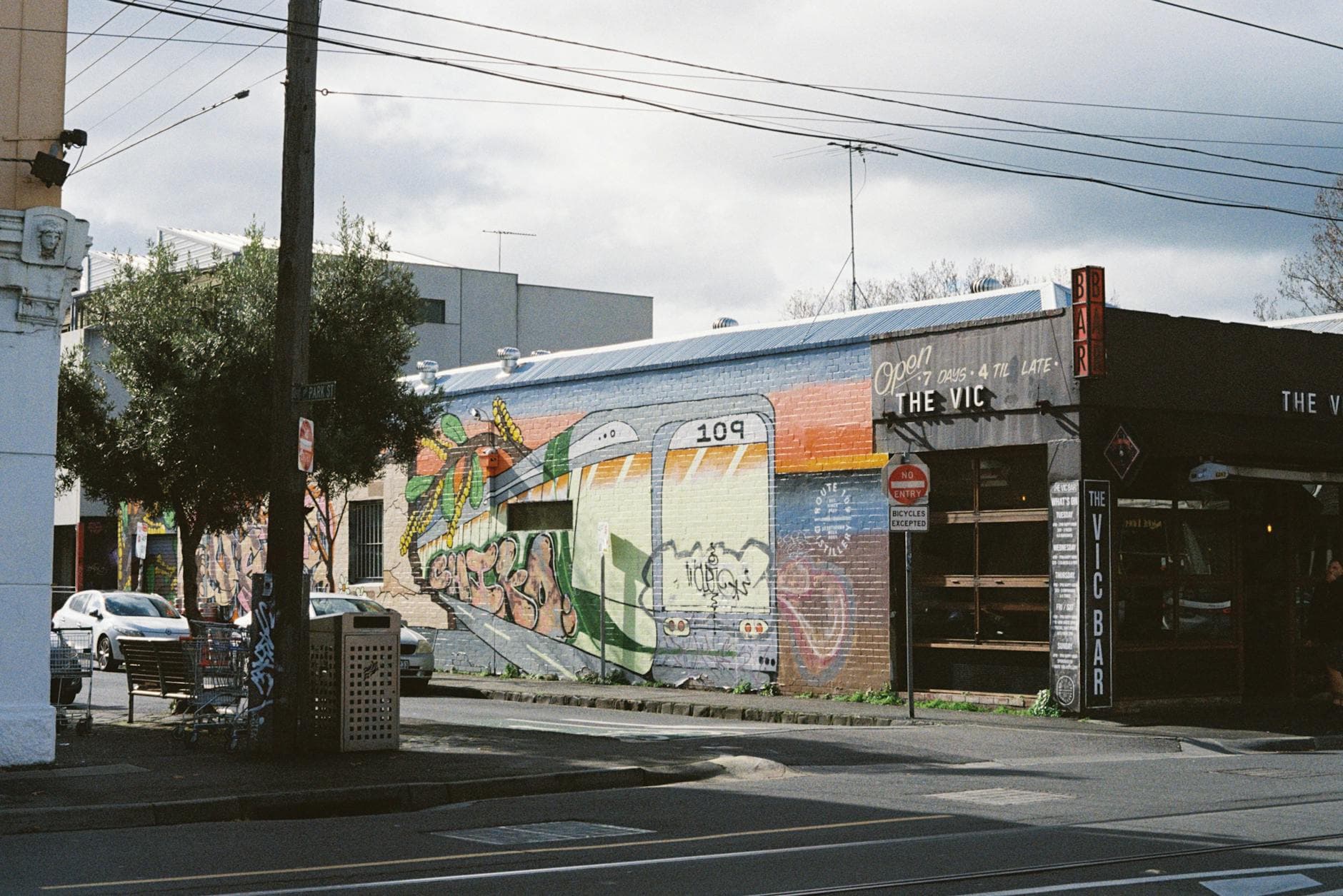 Colorful street art mural on a wall in Melbourne, Australia featuring a tram and vibrant designs.