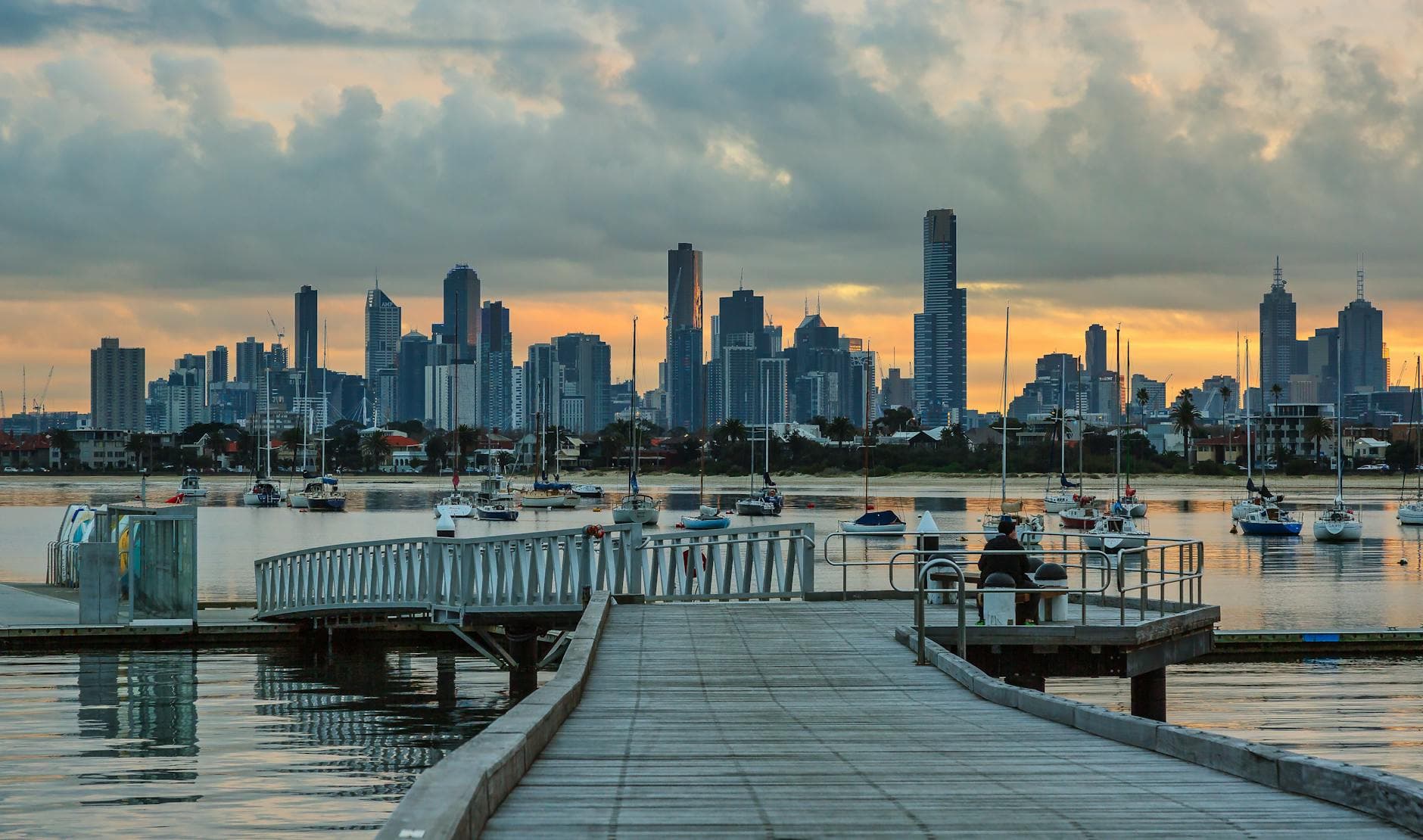 Panoramic view of Melbourne skyline during sunset, captured from St Kilda Pier with boats on the water.