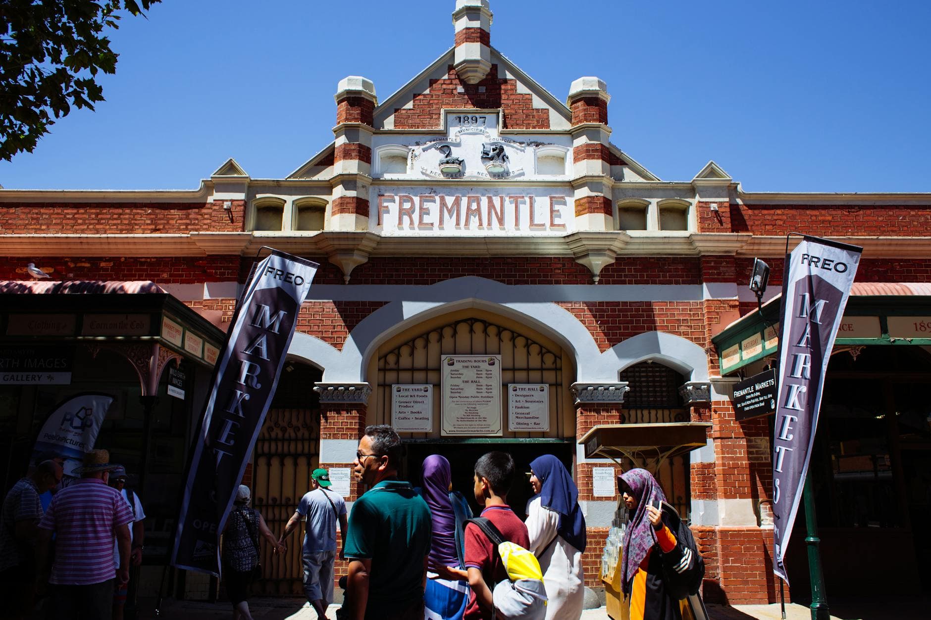 The entrance to Fremantle Market with people milling about on a sunny day.