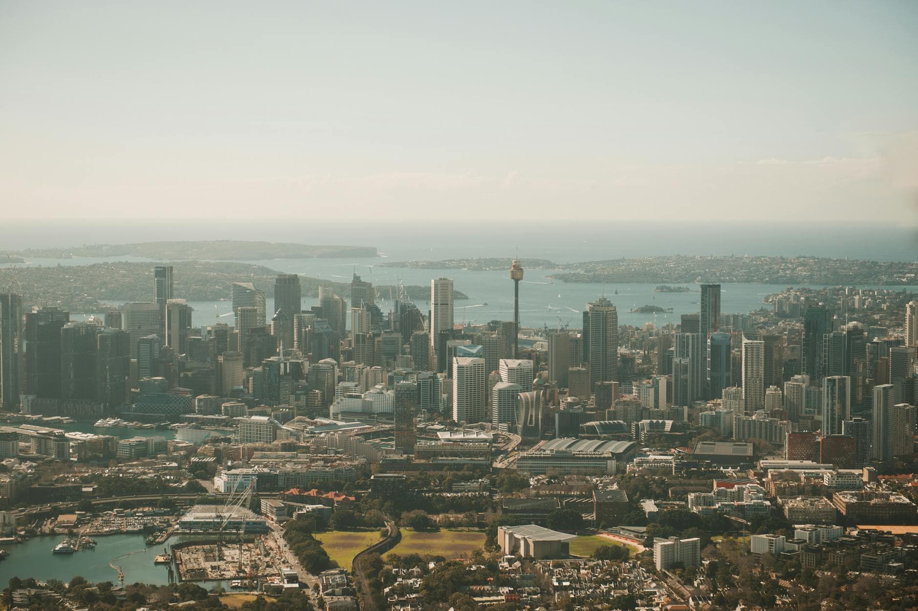 An expansive aerial view of Sydney's urban skyline with iconic architecture and the coastline.
