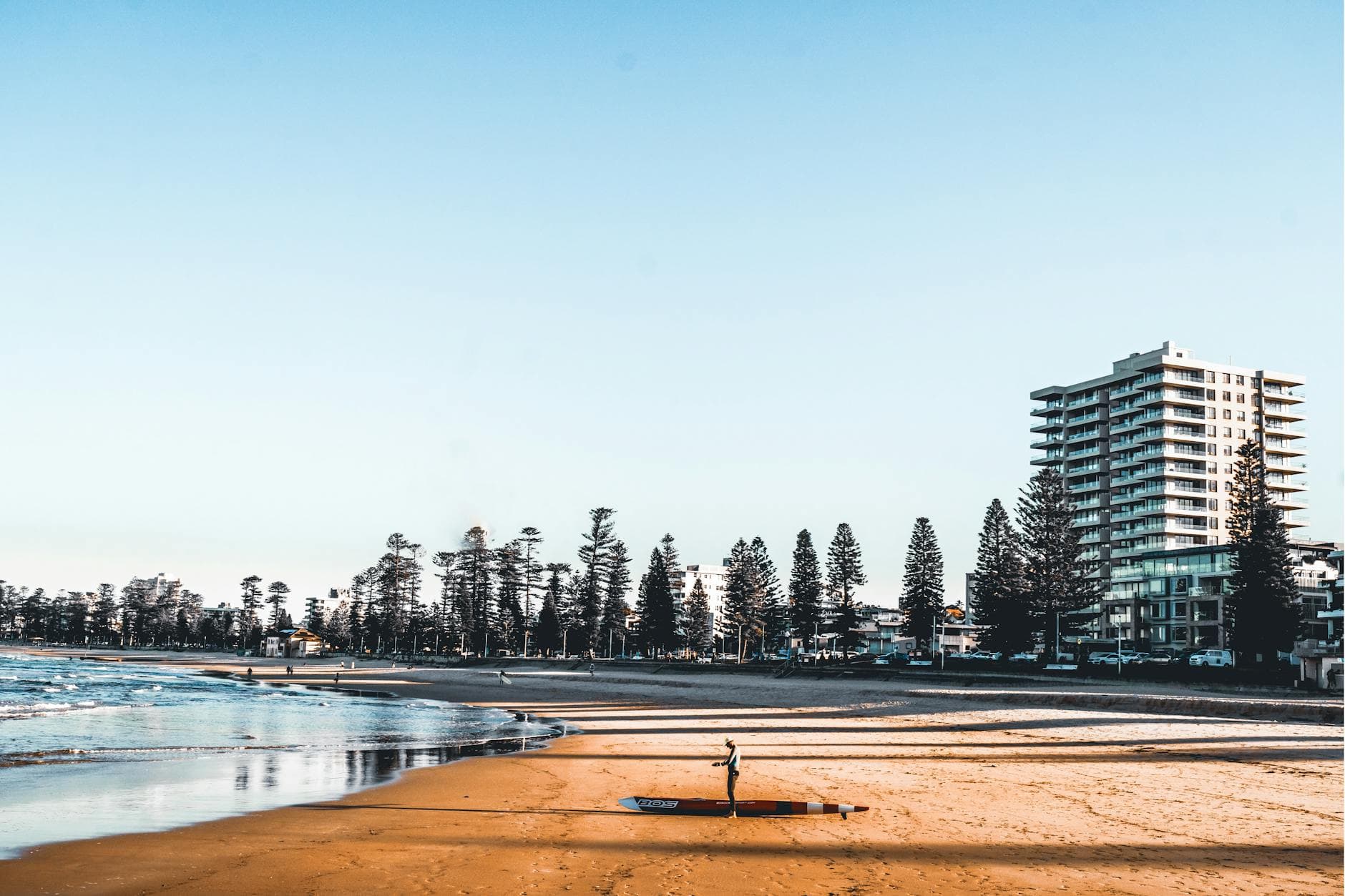 A surfer prepares to hit the waves on Manly Beach in Sydney during a beautiful summer morning.