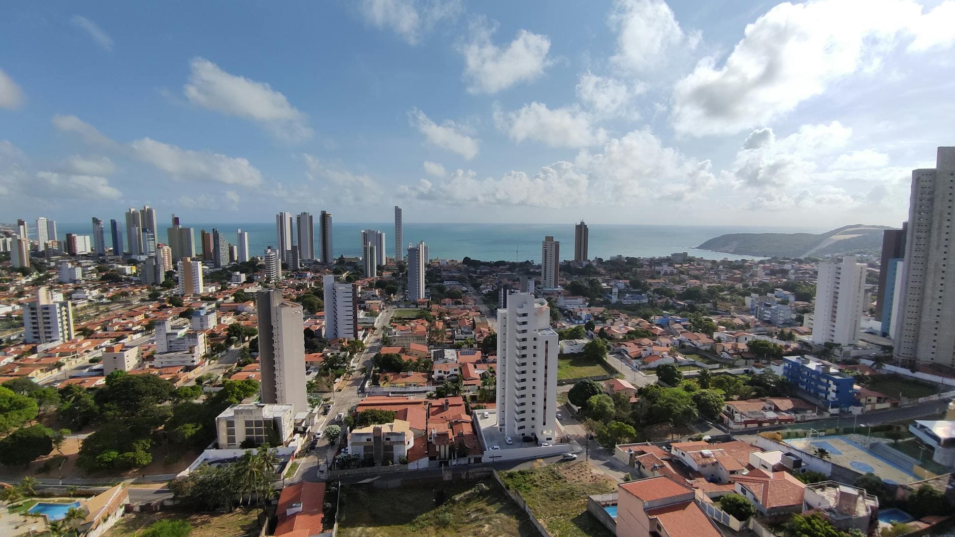 Aerial view of Natal, Brazil showcasing the skyline and Ponta Negra Beach under a sunny sky.