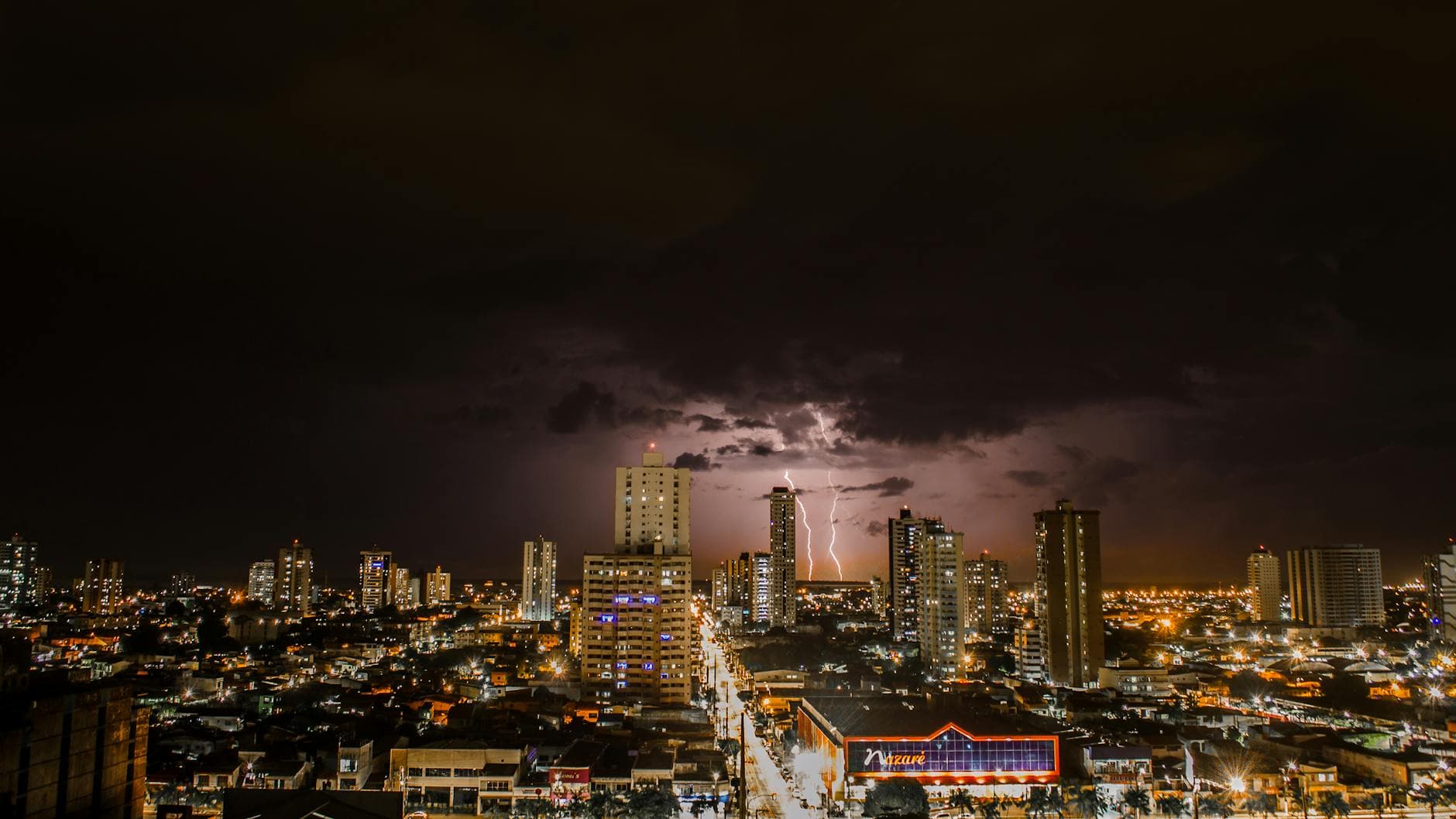 A vibrant city skyline illuminated by lightning against a dramatic night sky.