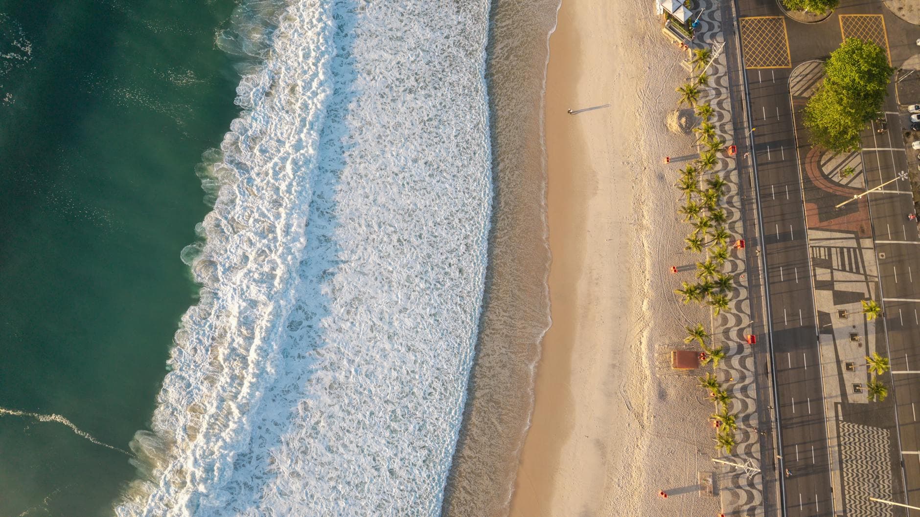 Stunning aerial shot of a Rio de Janeiro beach with golden sunlight highlighting the waves and coastline.