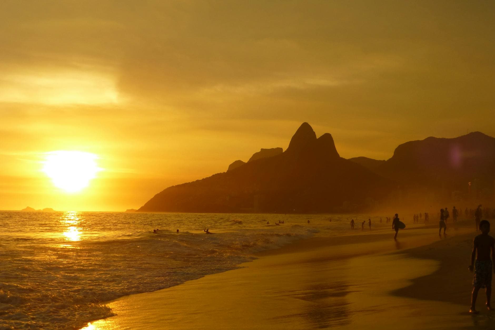 Captivating sunset over Ipanema Beach with people silhouetted against the golden sky.