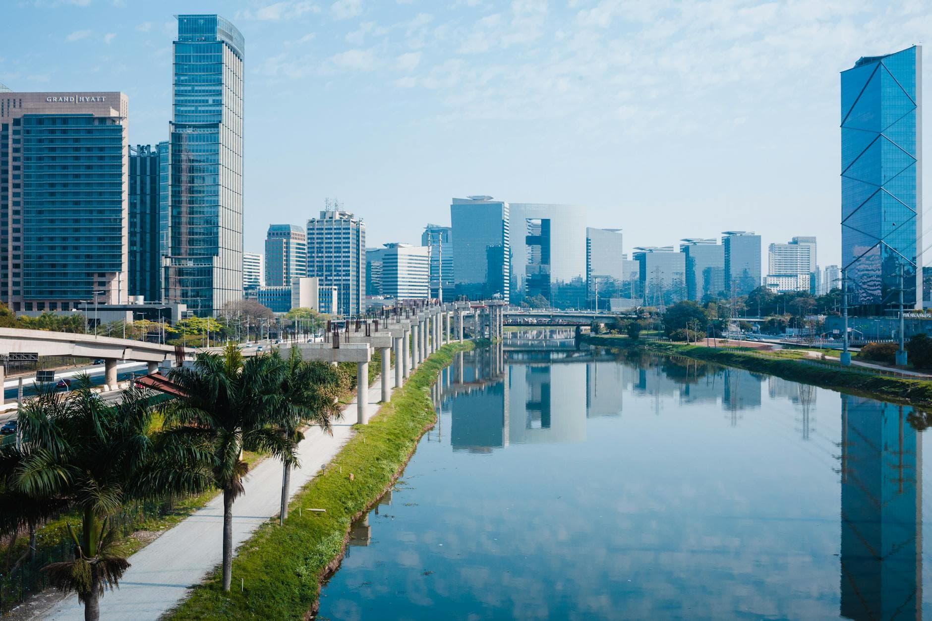 Stunning view of a modern city skyline reflecting in the river with clear blue sky.