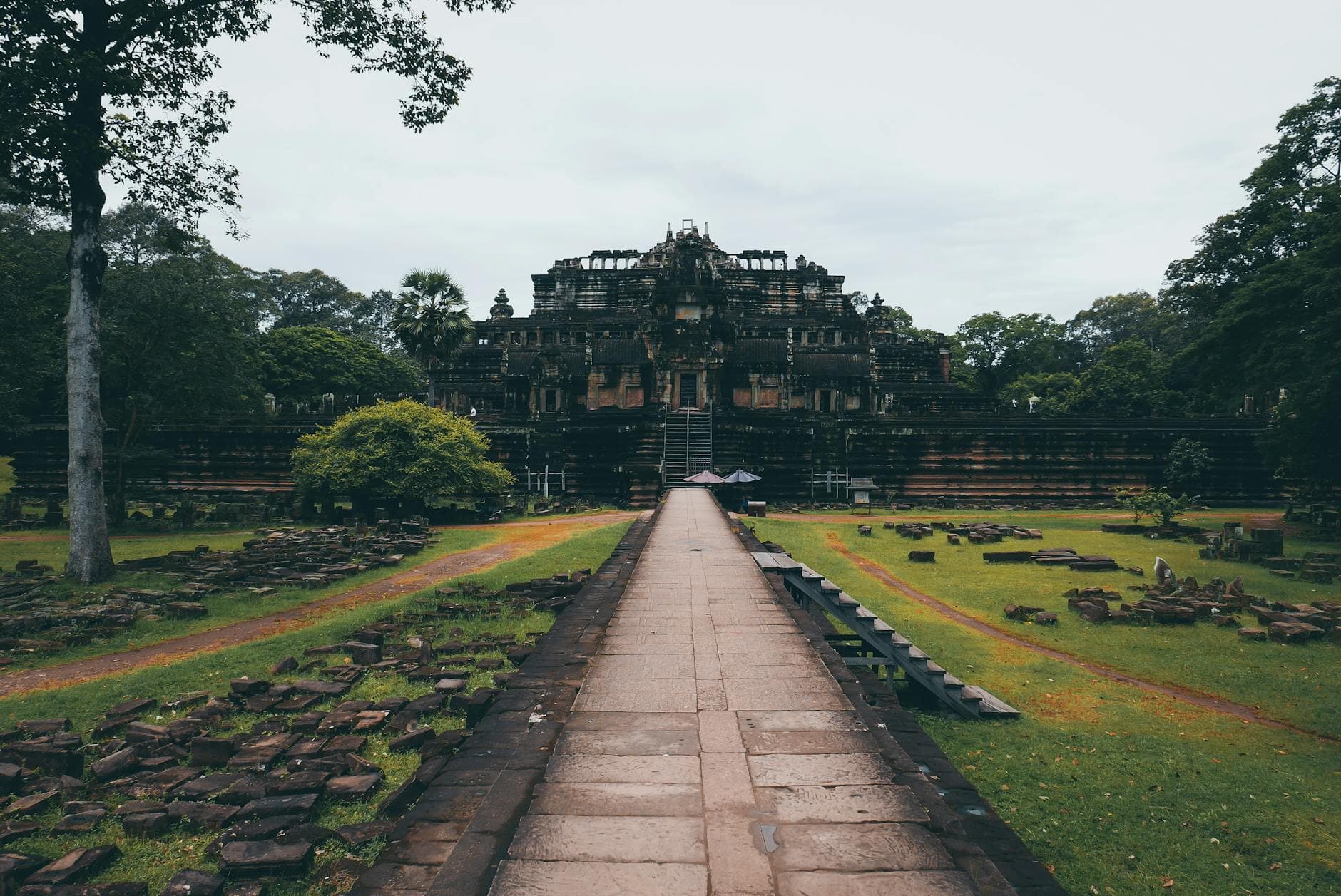Historic Baphuon Temple at Angkor, Cambodia, amidst lush greenery and ancient ruins.