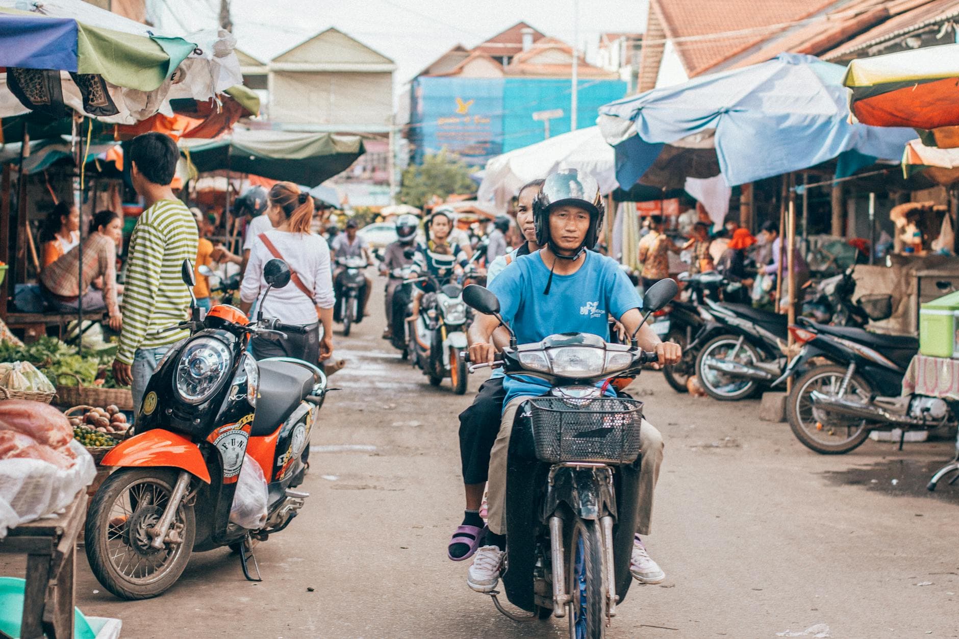 Motorcyclists navigate a busy market street in Siem Reap, capturing the vibrant local culture.
