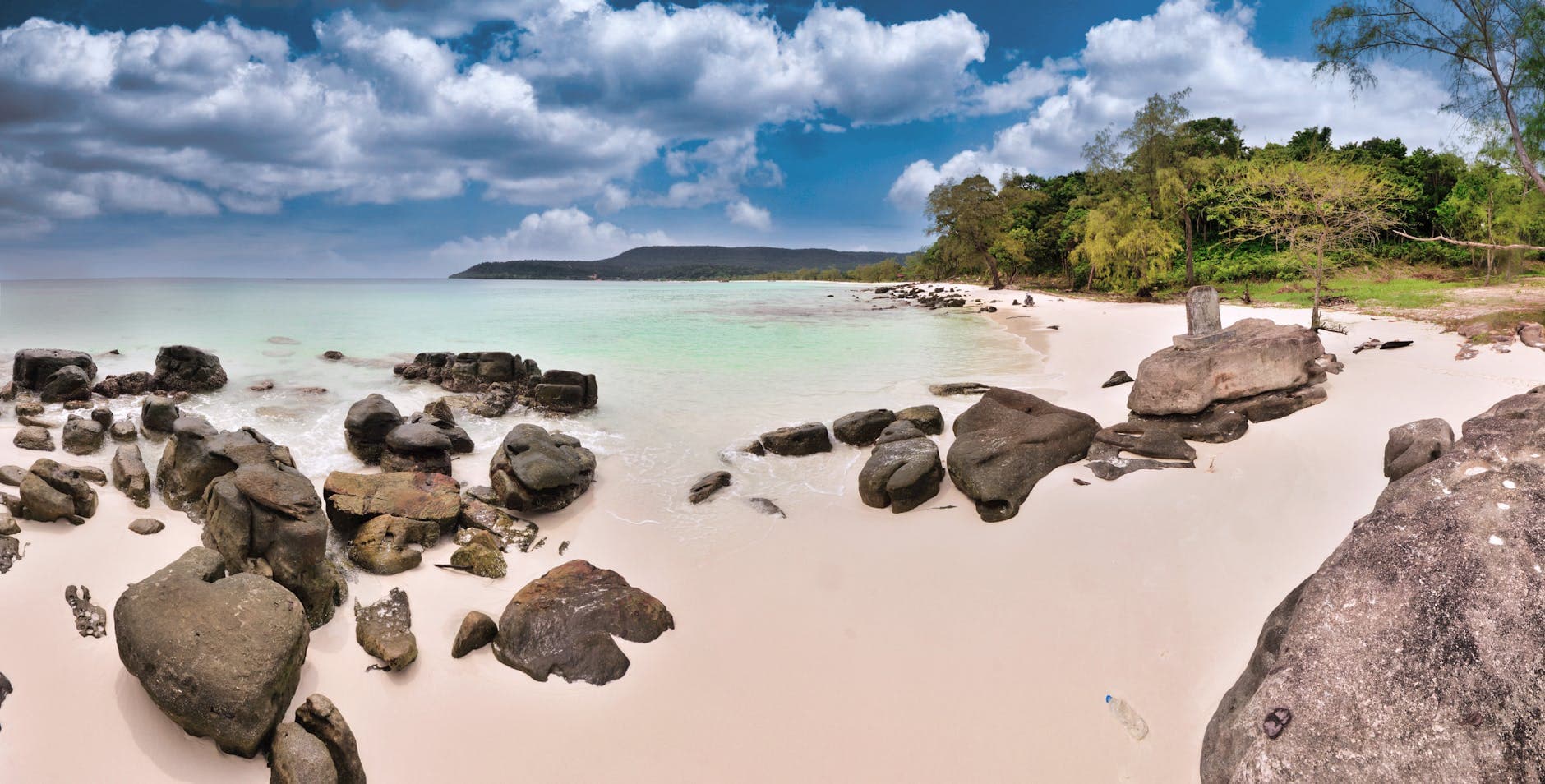 Tranquil Sok San Beach with clear waters and rocky shores in Cambodia.