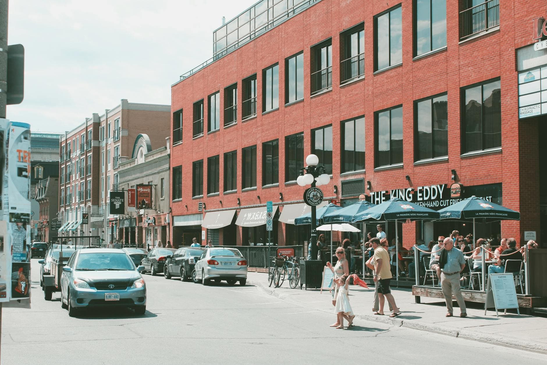 Vibrant street life in downtown Ottawa with cars, pedestrians, and outdoor cafes on a sunny day.