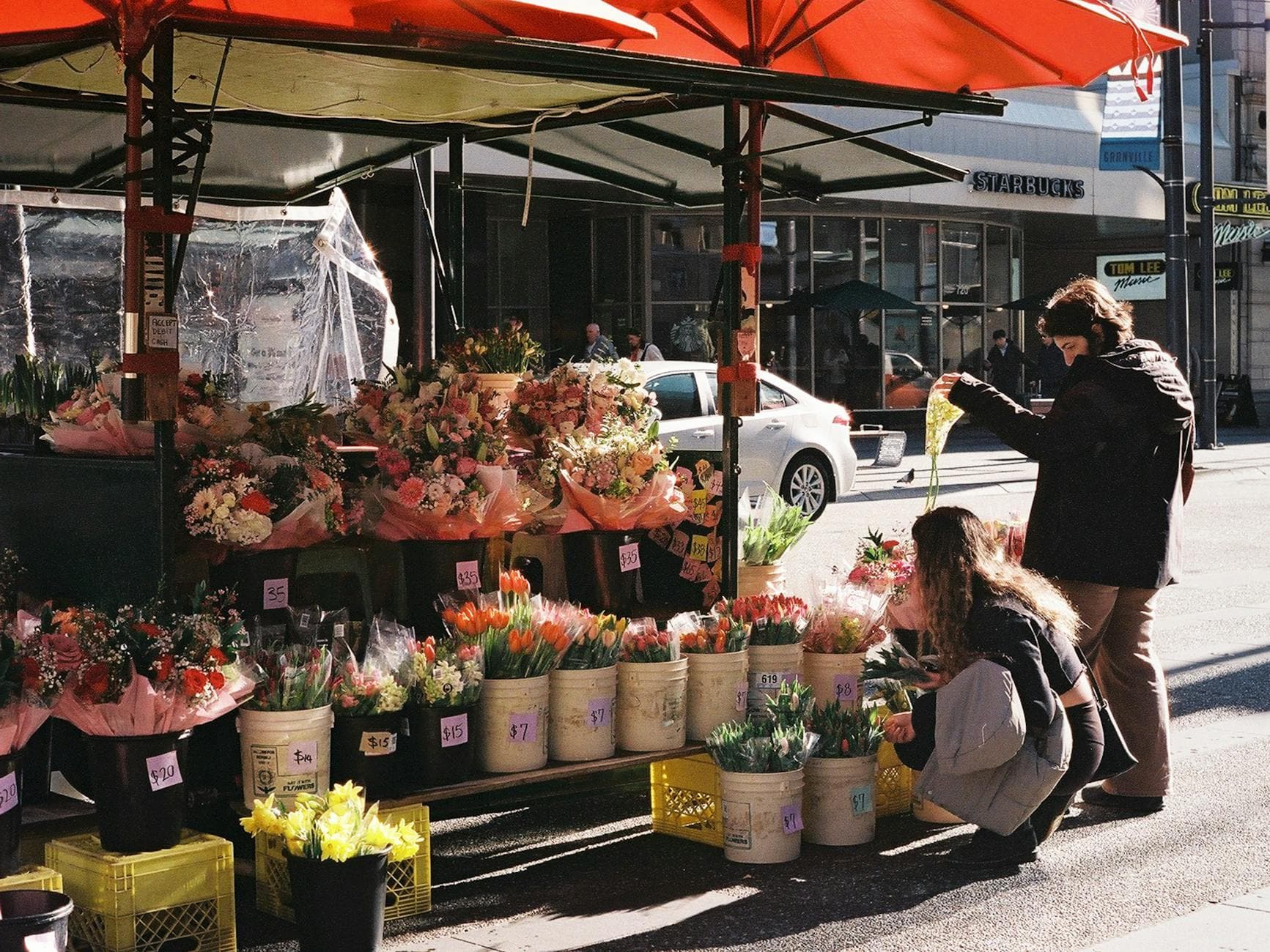 A lively flower stand in Vancouver showcasing vibrant blooms under sunlight on Granville Street.
