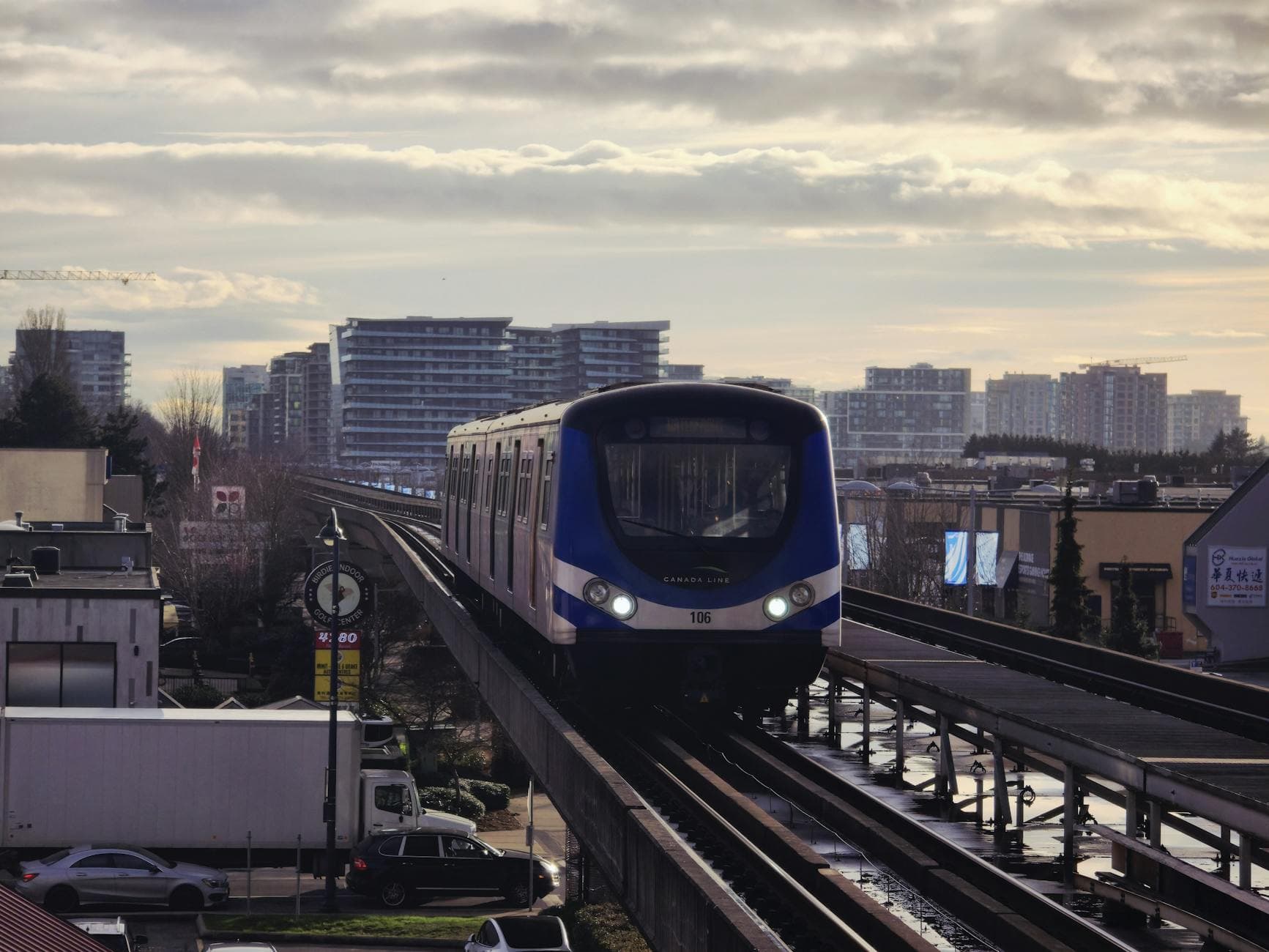 SkyTrain traversing Richmond, BC with cityscape and moody evening light.