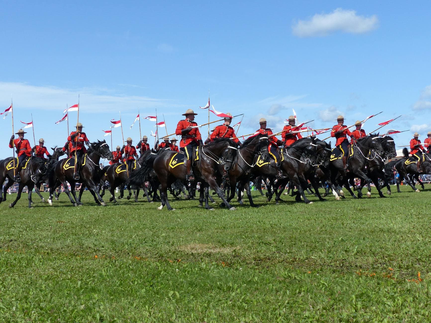 Canadian Mounties in red uniforms riding horses at an outdoor event.