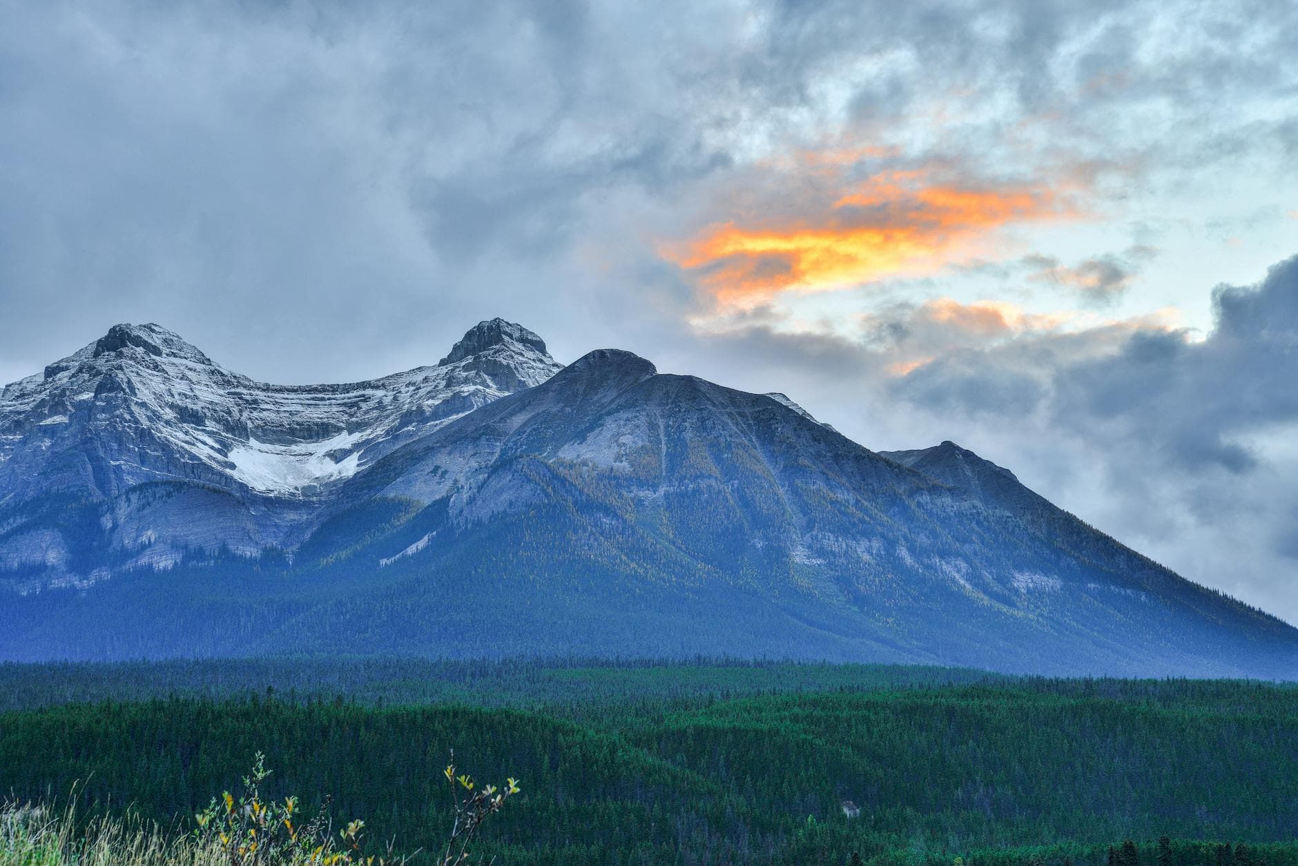 Stunning view of a snow-capped mountain in Banff, Alberta with dramatic sky at sunset.