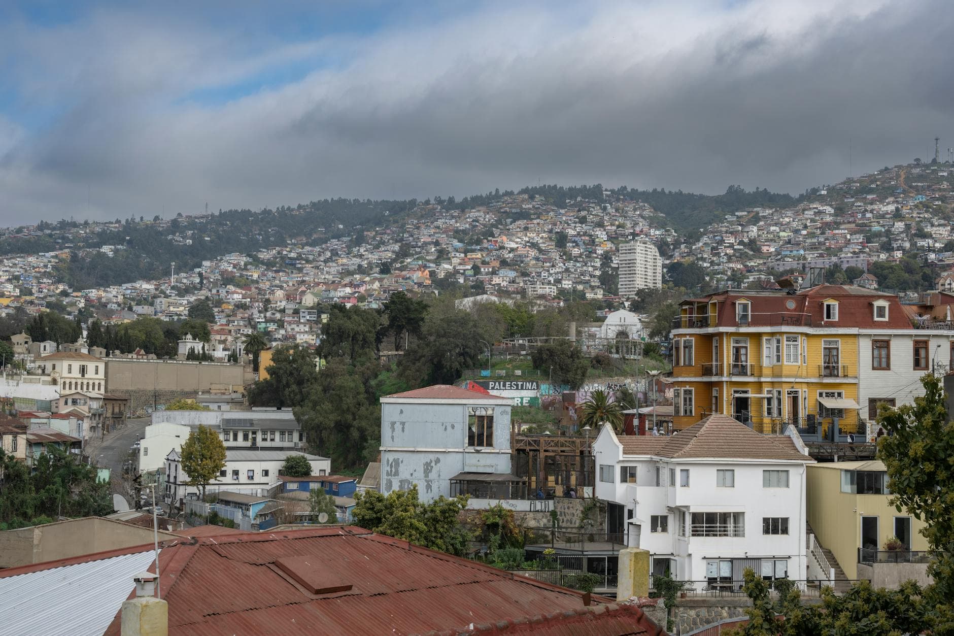 View of vibrant hillside houses in Valparaíso, Chile, under cloudy skies.