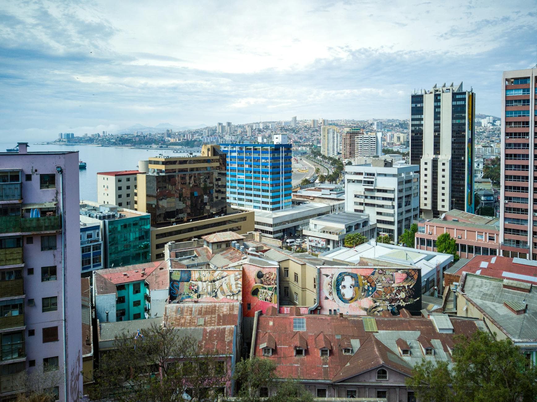 A dynamic view of Valparaíso city with colorful graffiti and ocean backdrop.