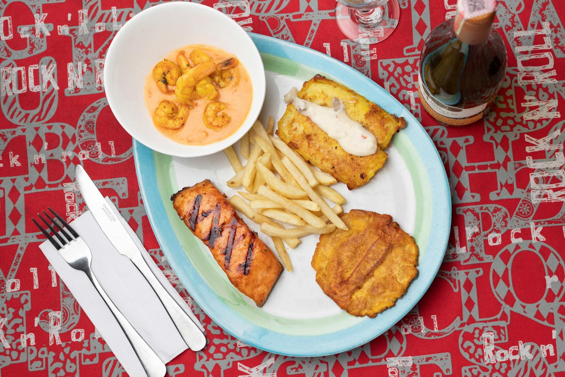 Delicious Colombian seafood platter featuring shrimp, fried plantains, and fish with a creamy sauce.