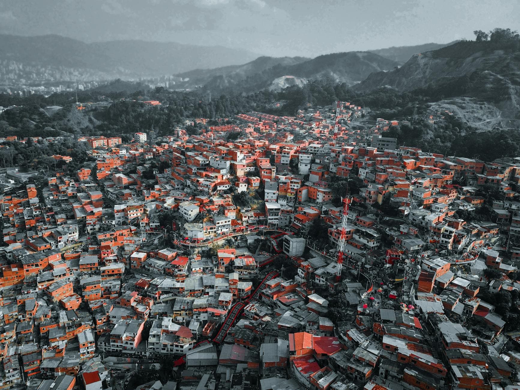 Colorful urban landscape of Medellín viewed from above, showcasing dense housing and surrounding hills.