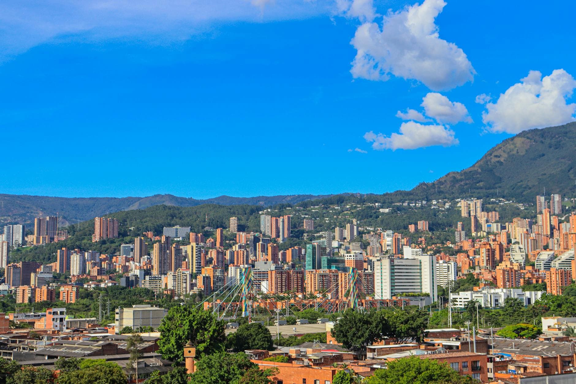 A stunning view of Medellín, Colombia with a backdrop of mountains and clear blue skies.