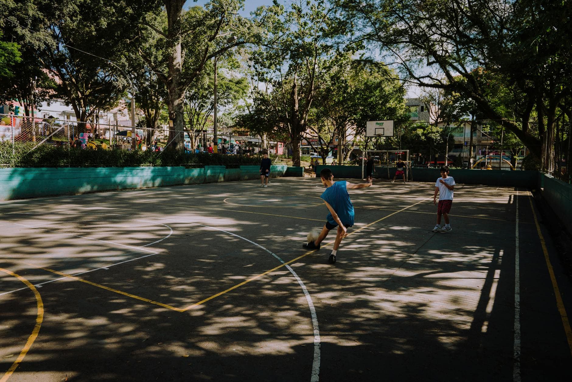 Vibrant scene of teenagers playing soccer on a sunny day in a Medellín park.