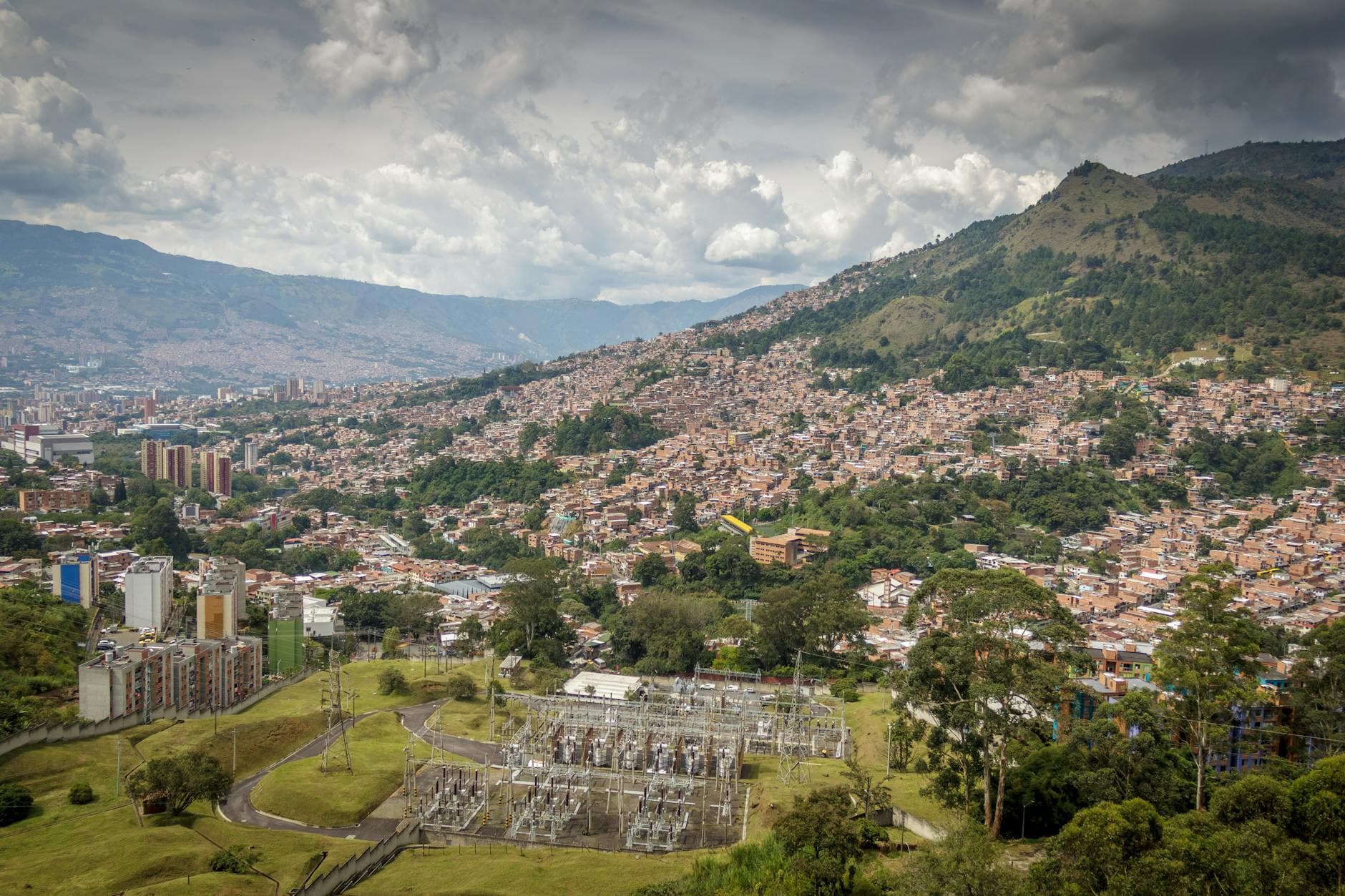 Explore the bustling cityscape of Medellin with its urban sprawl and mountainous backdrop on a summer day.