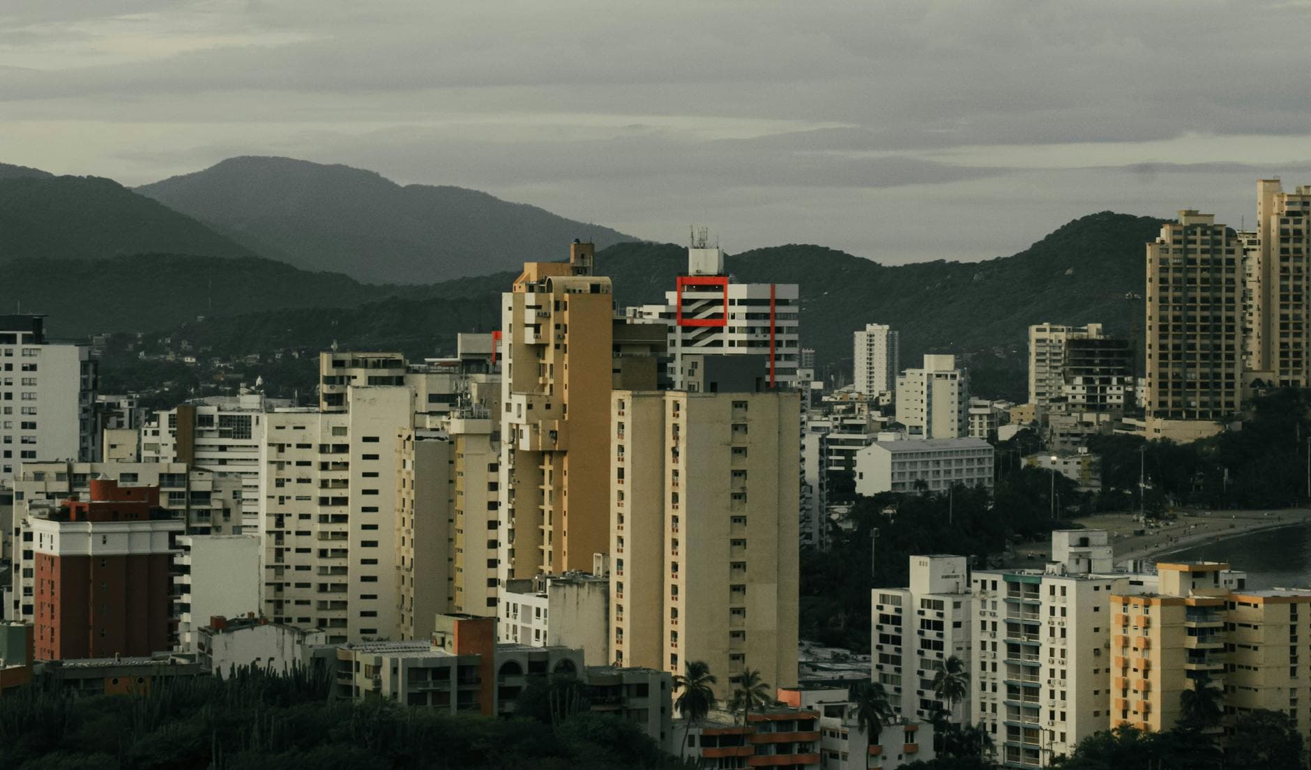 Elevated view of Santa Marta's urban skyline with distant mountains under a cloudy sky.