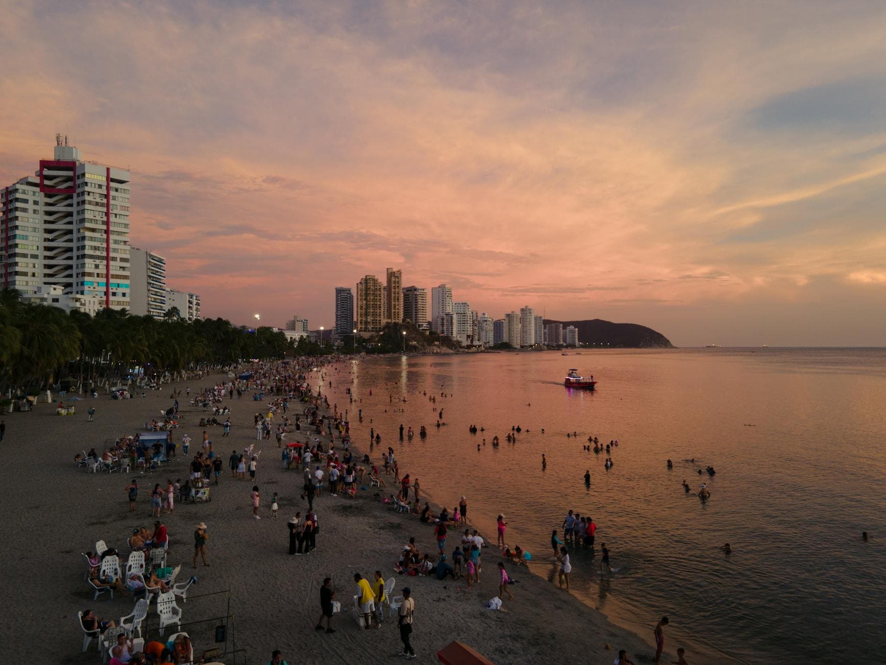 A bustling beach scene at sunset with a vibrant city skyline, capturing summer vibes and leisure.