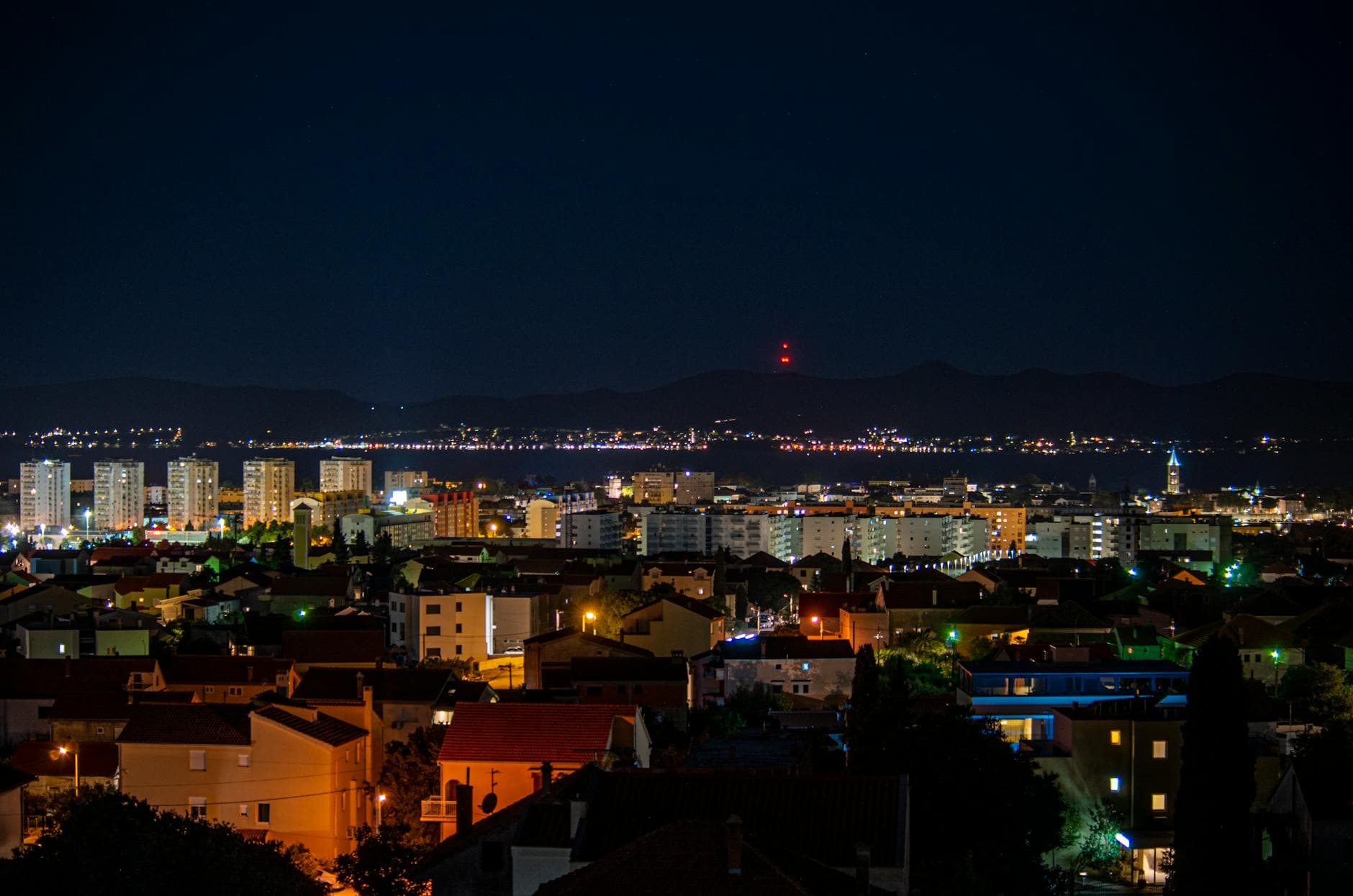 A breathtaking aerial view of Zadar cityscape illuminated at night, capturing vibrant urban life.