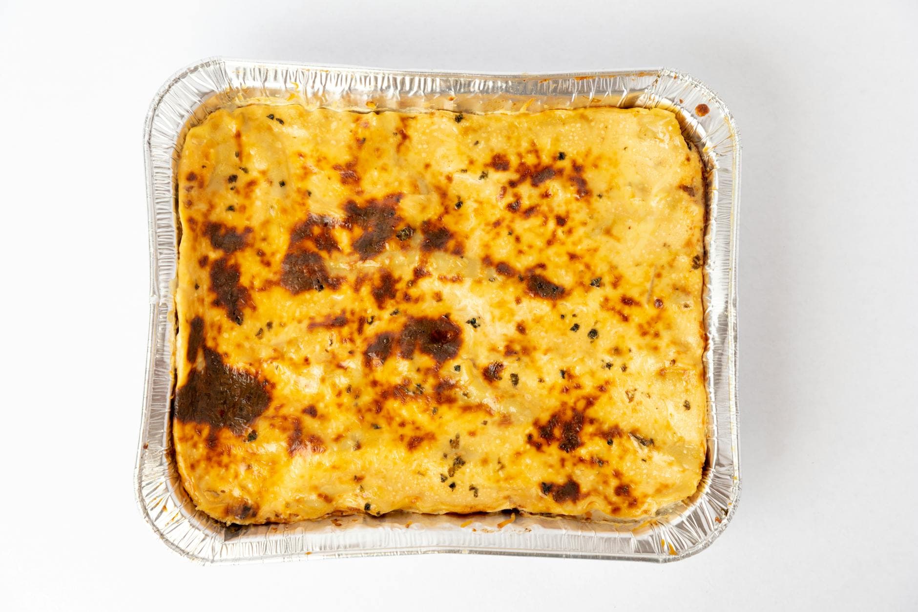 A freshly baked lasagna with golden cheese crust captured from above in a foil tray.