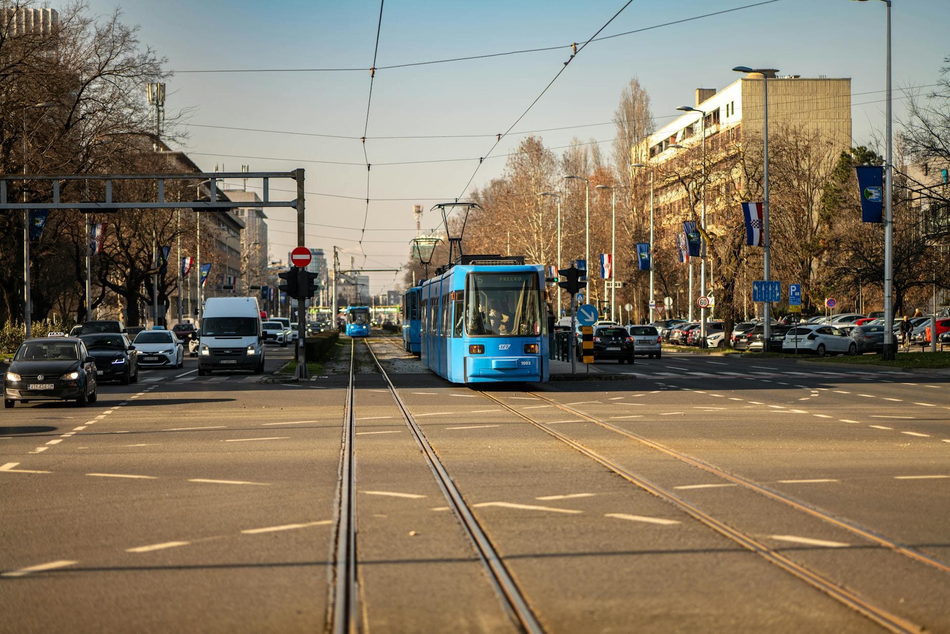Blue tram traversing a busy street in Zagreb, Croatia's urban landscape.