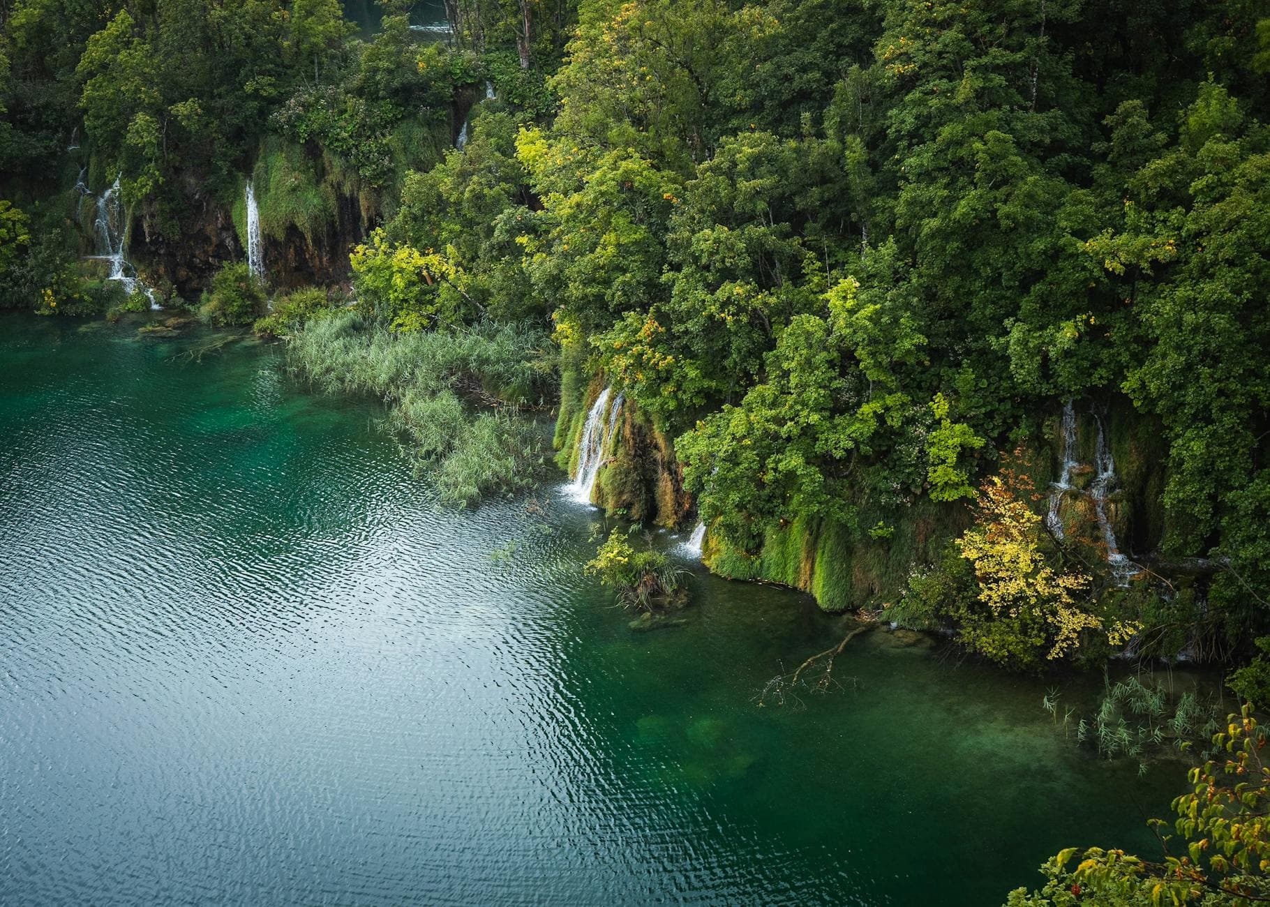 Aerial view of lush waterfalls and turquoise waters in Plitvice Lakes, Croatia.