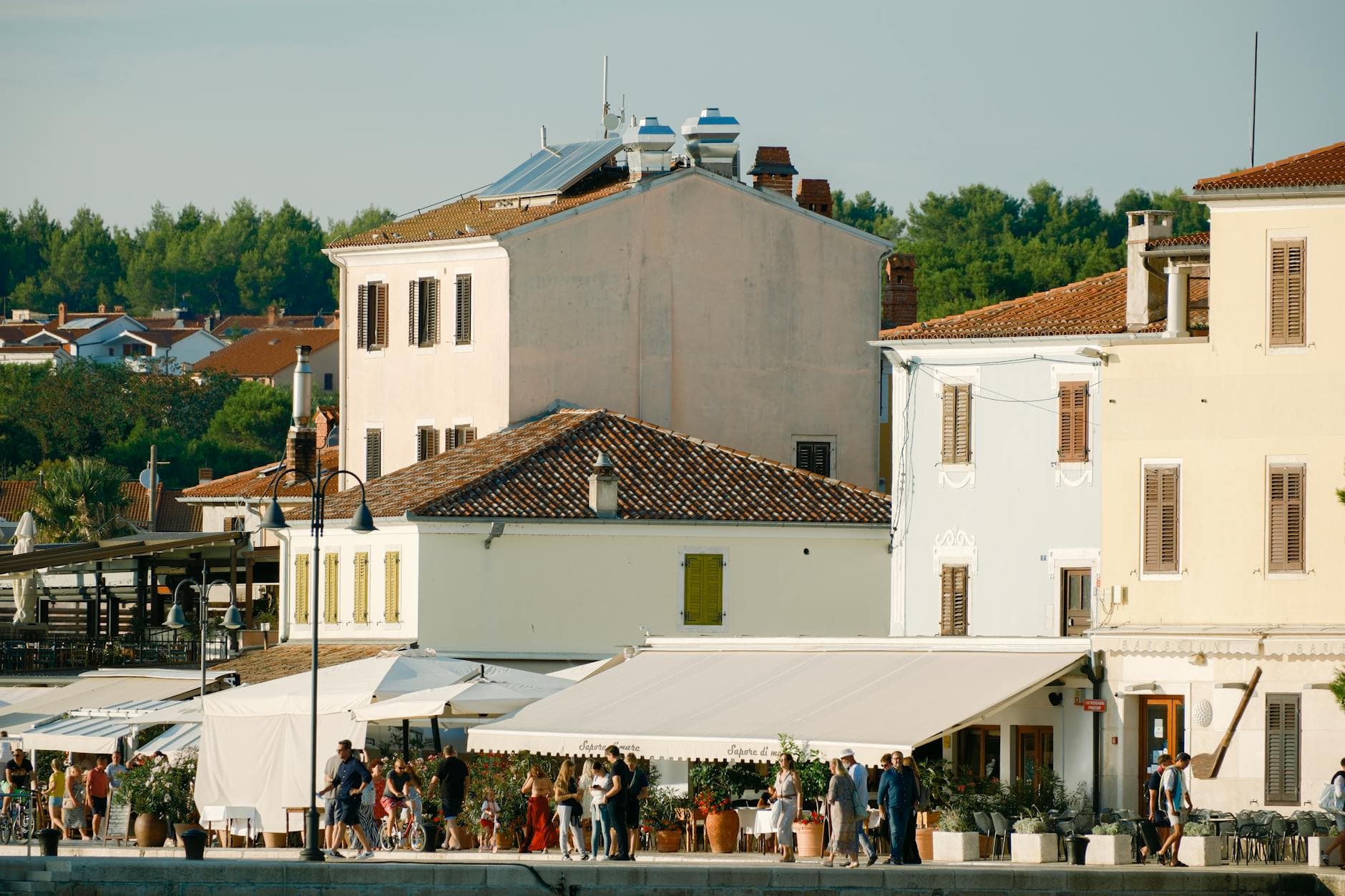 Scenic view of coastal buildings in Croatia with people enjoying a sunny day.