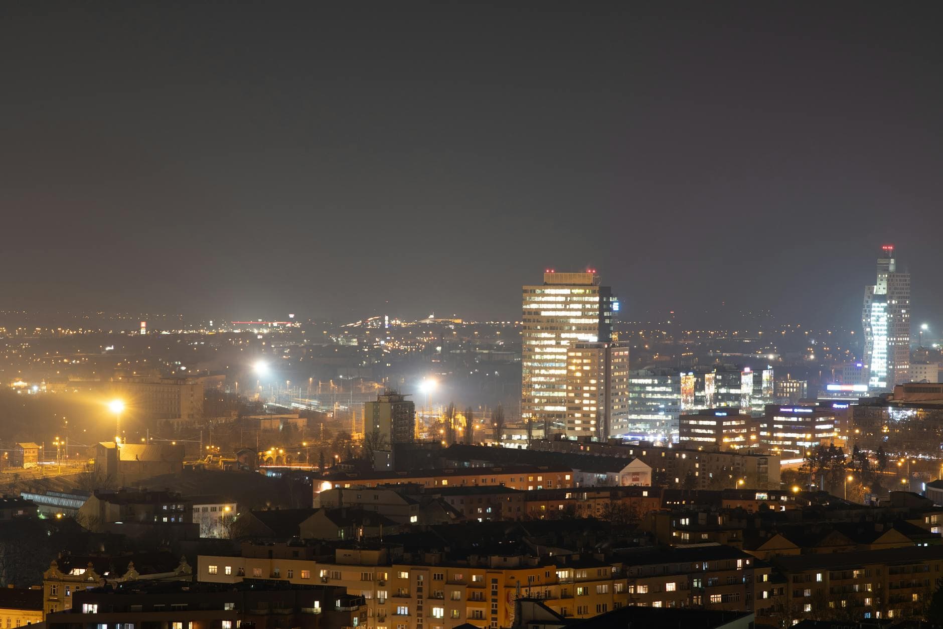 Skyline of Brno city at night with modern architecture and glowing city lights.