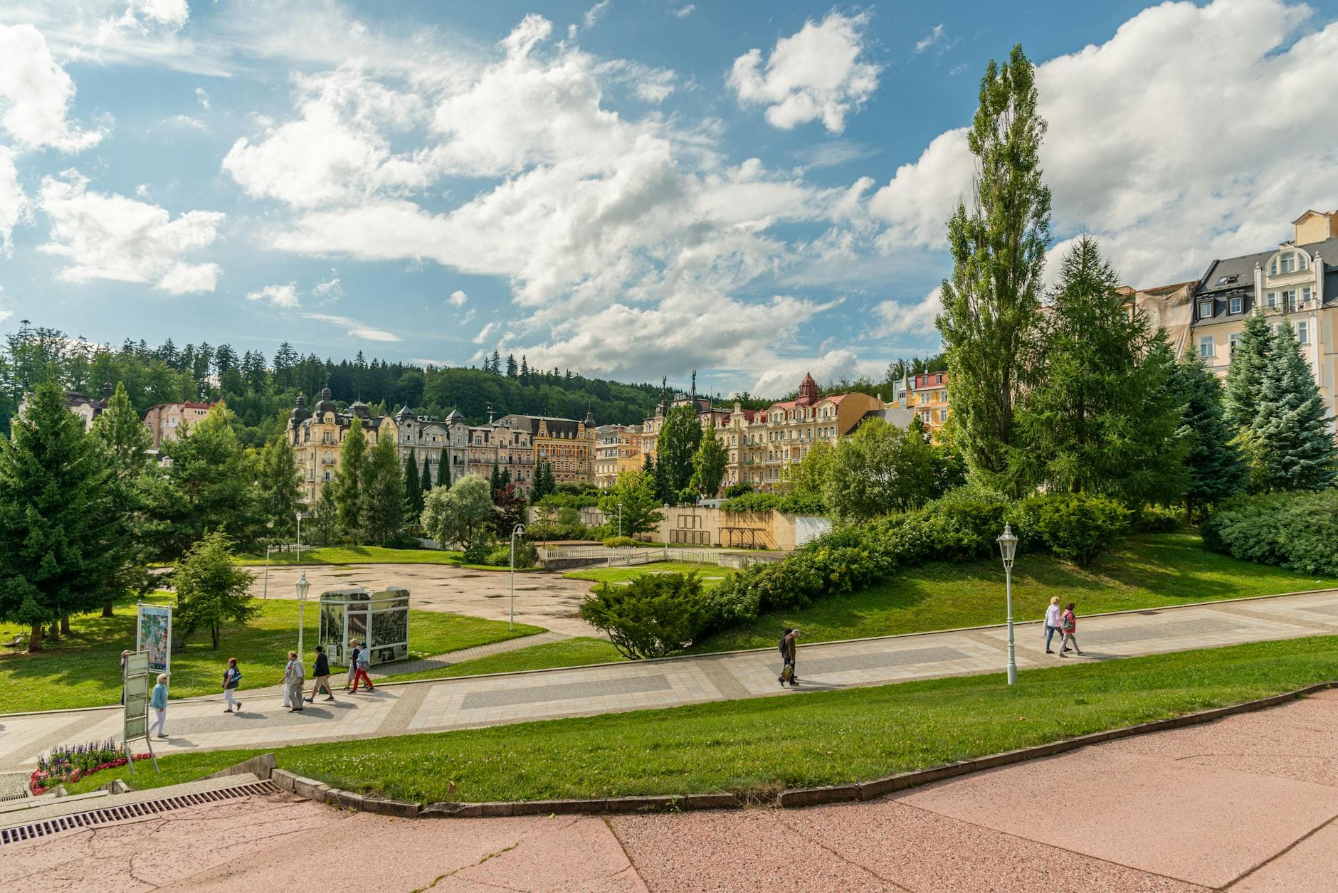 A scenic view of Mariánské Lázně showing historic architecture and lush greenery under a bright sky.