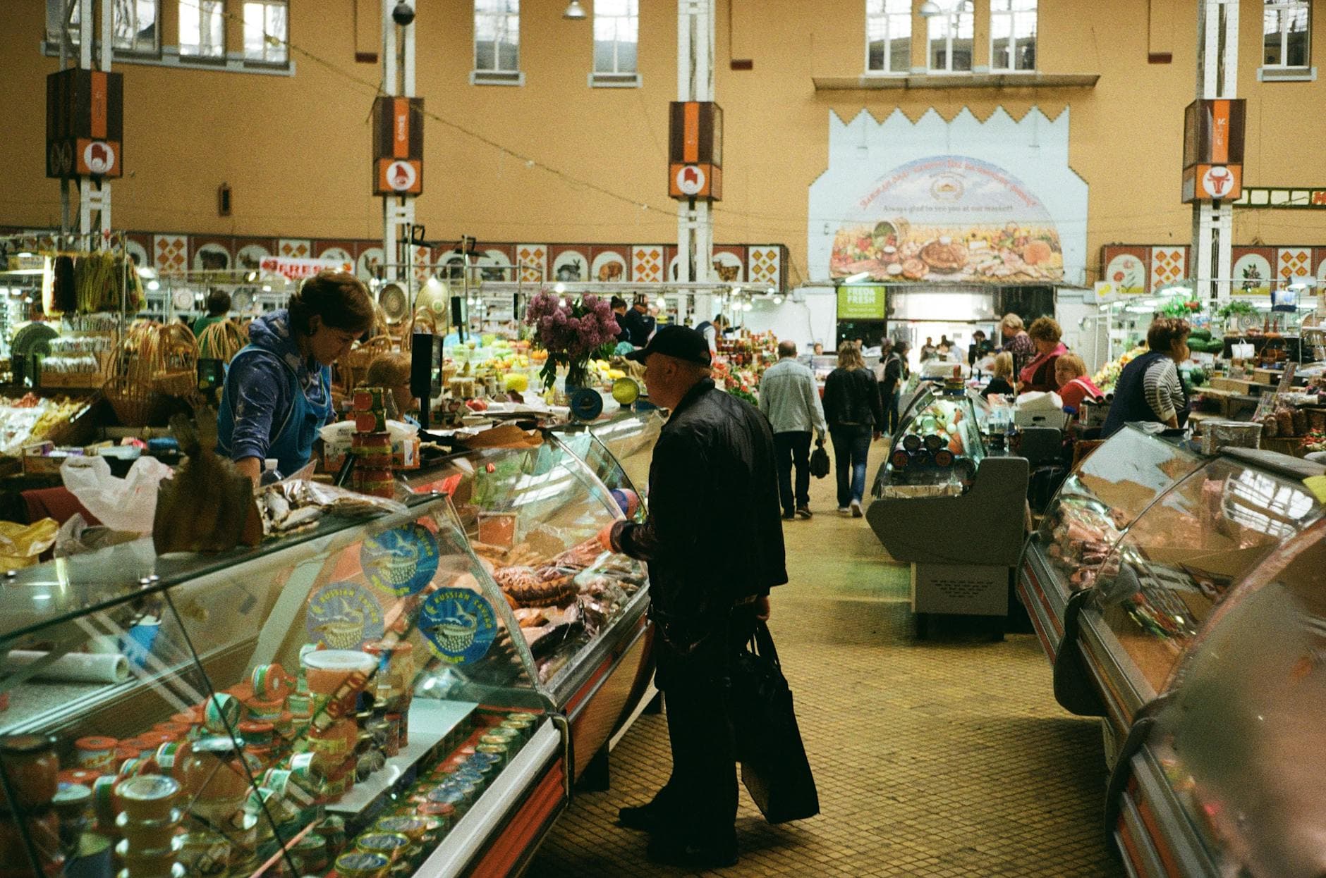Indoor market in Kyiv bustling with shoppers exploring fresh groceries and market stalls.