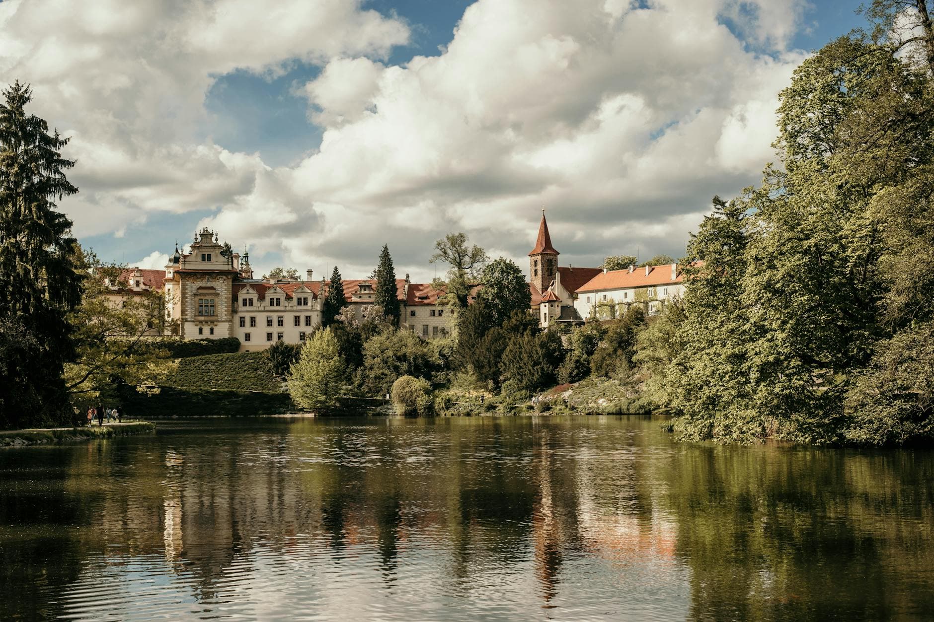 Explore the serene beauty of Pruhonice Park with its picturesque palace and pond view.