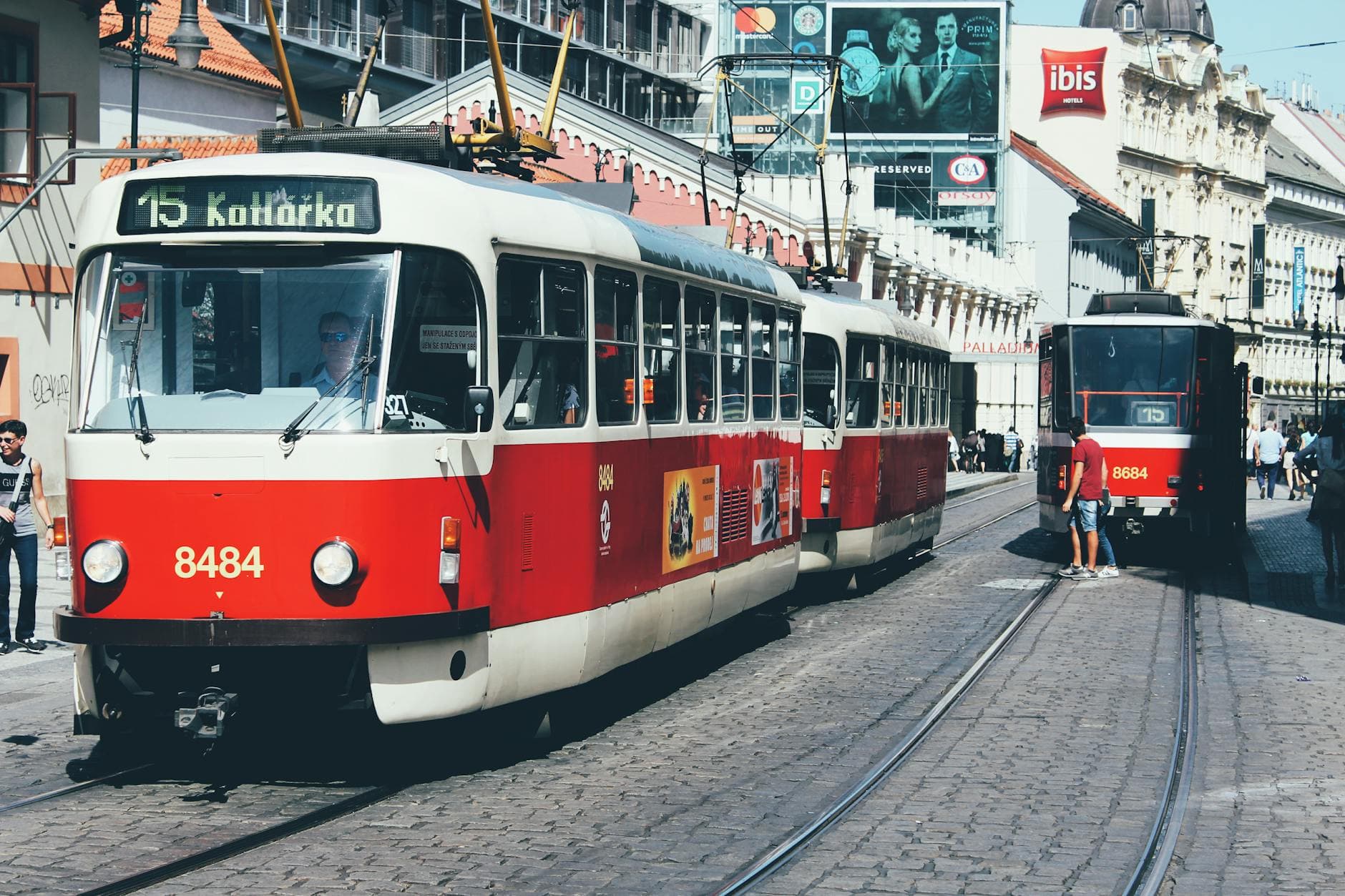 Classic red trams on a sunny day in a European city street, showcasing urban transport.
