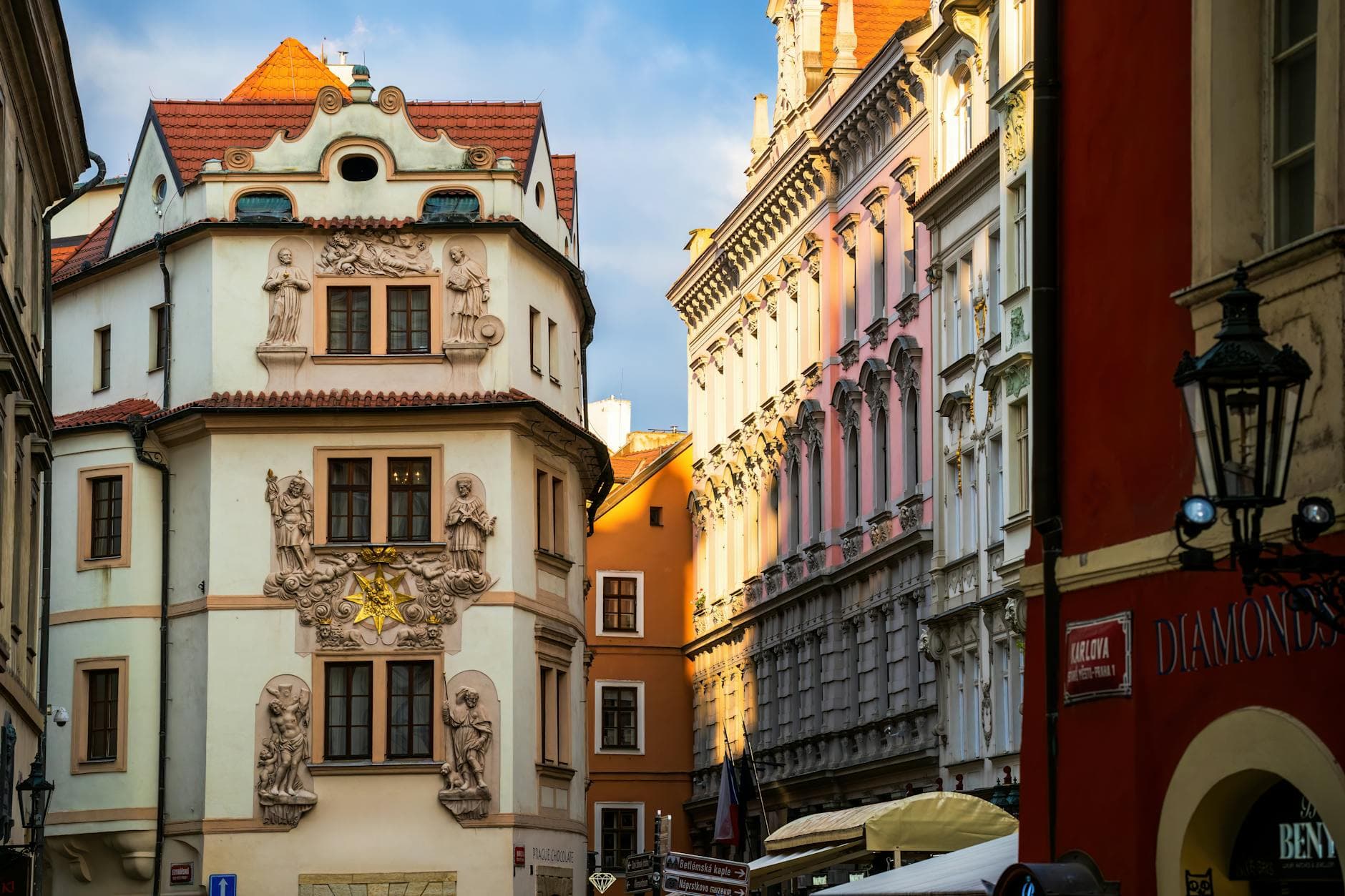 Charming street view of historic architecture in Prague city center, showcasing ornate facades in golden sunlight.