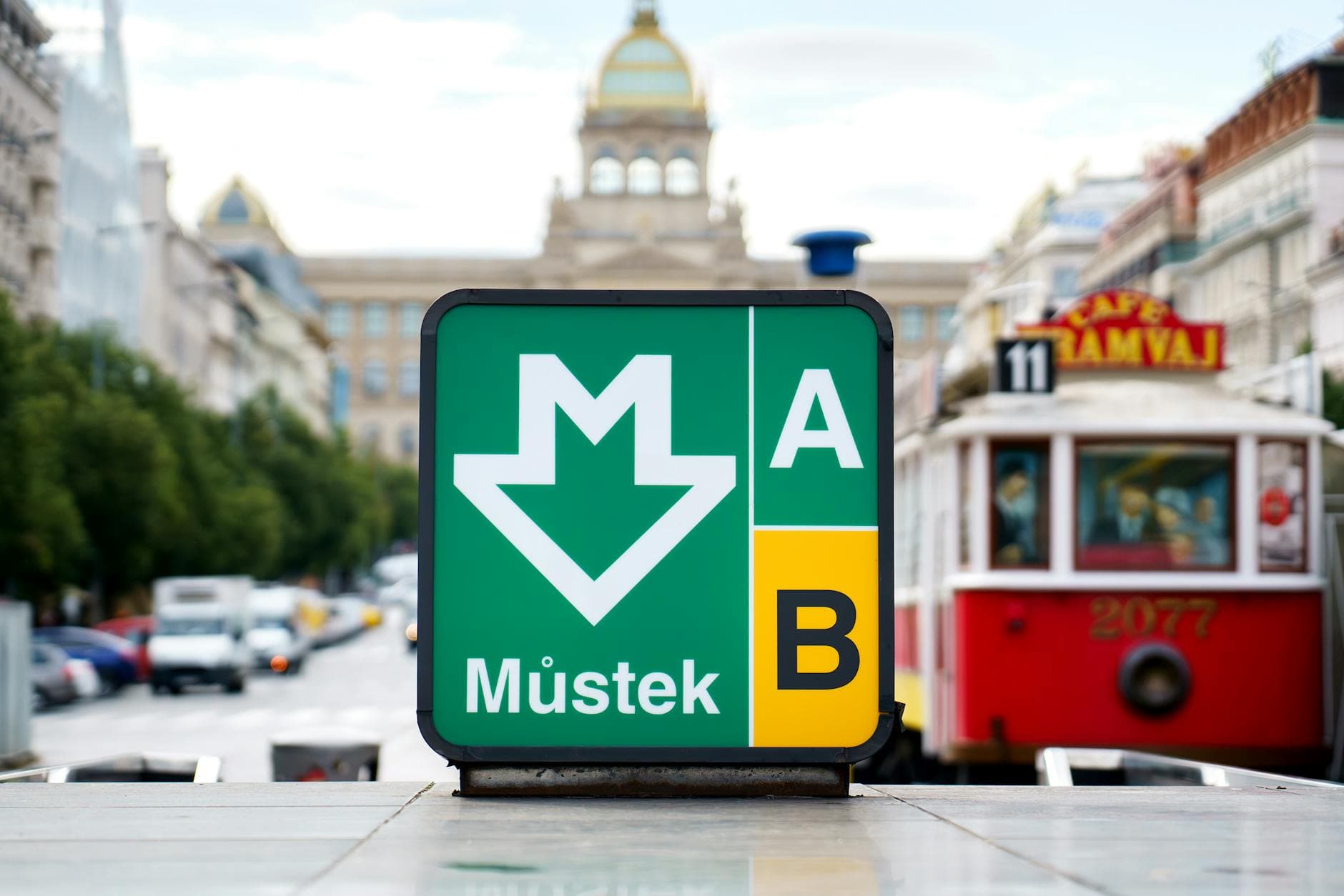 Vibrant shot of Můstek metro sign and tram in bustling Prague city center.