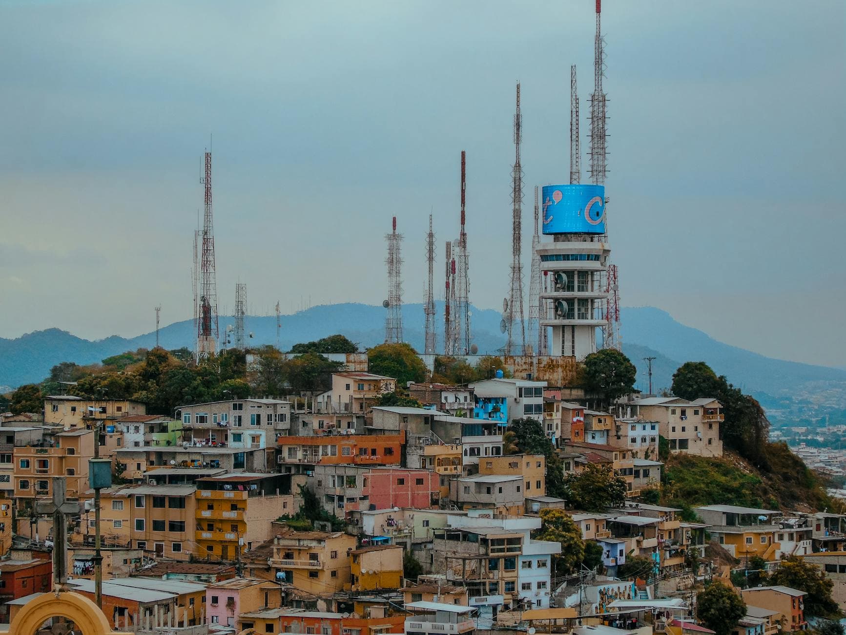 A vibrant view of Guayaquil's skyline with telecommunication towers over colorful hillside houses in Ecuador.