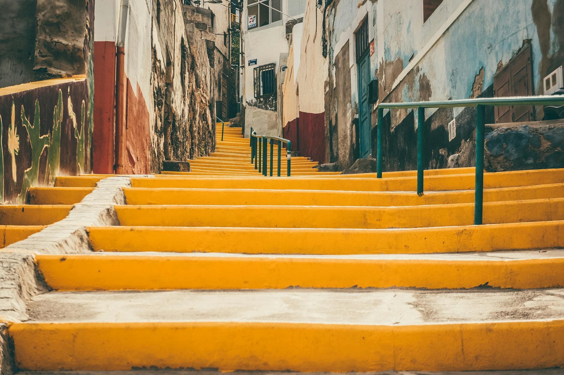 Bright yellow stairs in a picturesque street of Las Palmas, Gran Canaria, showcasing urban charm.