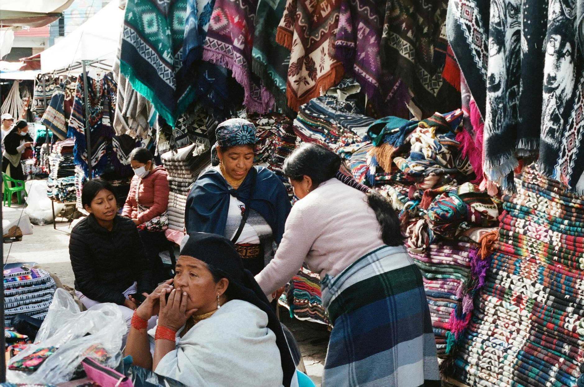 Colorful textiles and local vendors at Otavalo market in Ecuador, showcasing traditional garments and crafts.