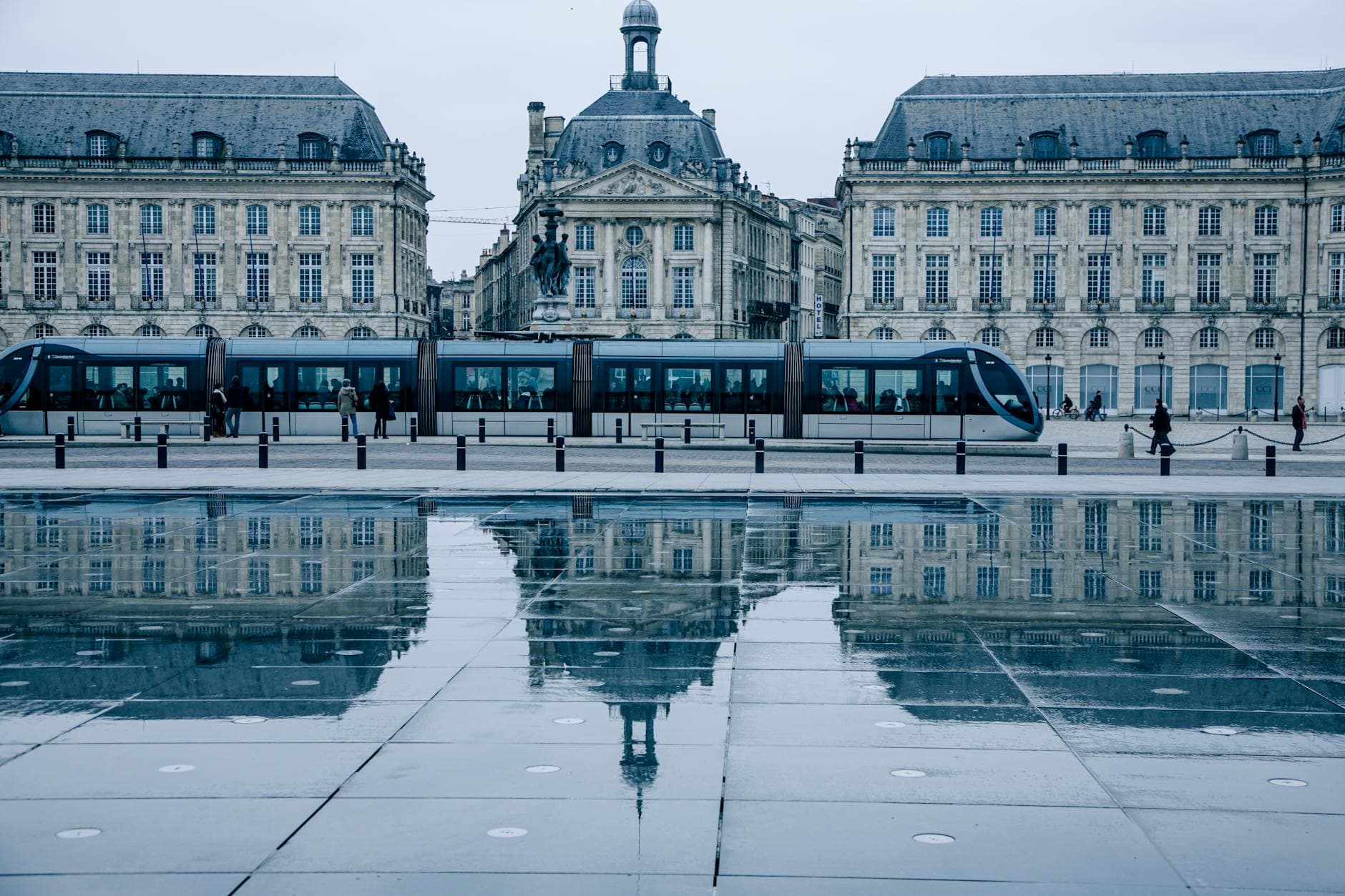 Tram passing by the historic Place de la Bourse in Bordeaux, reflecting on the Miroir d'eau.