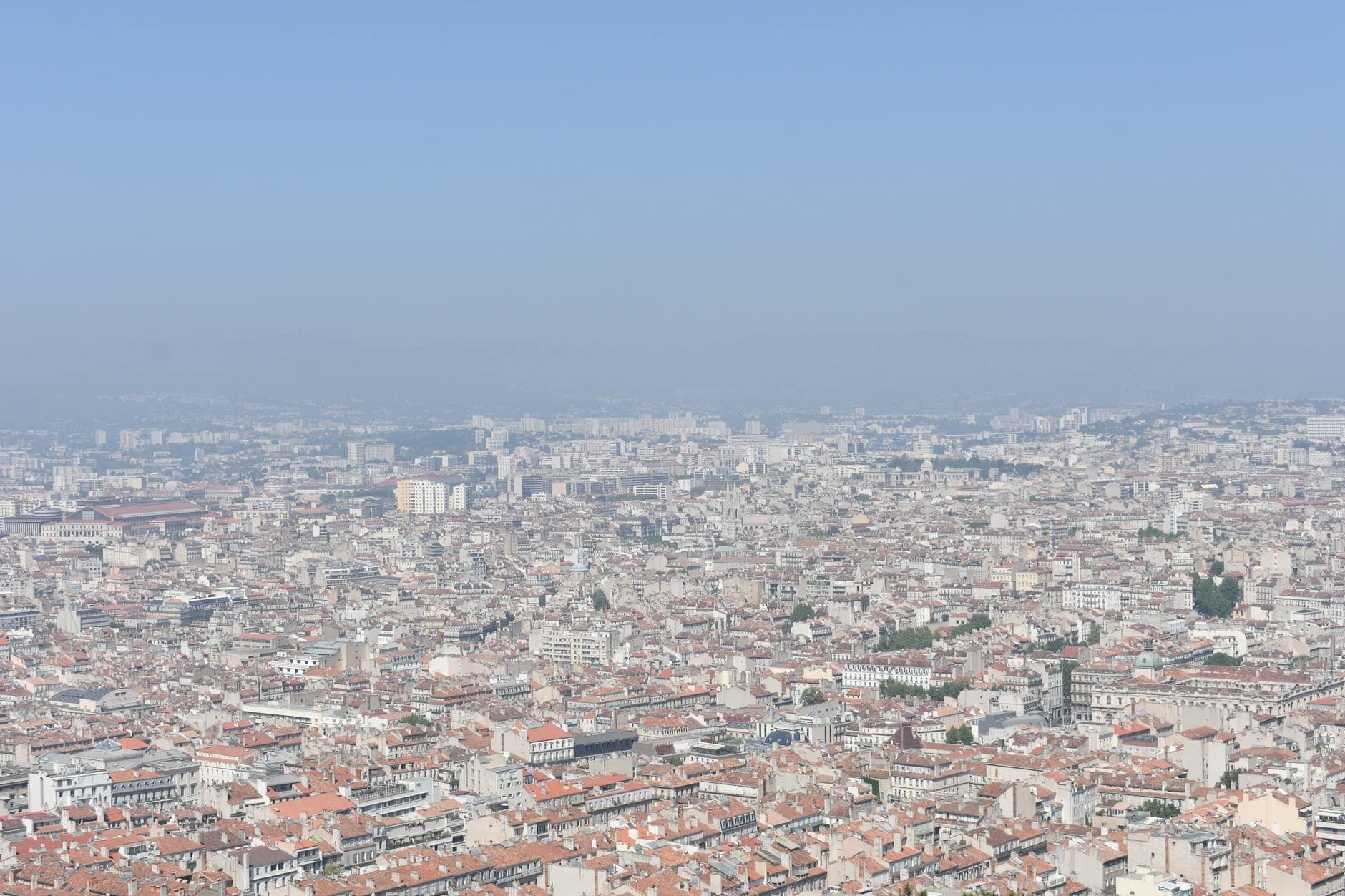 Aerial shot of Marseille, showcasing the city's sprawling urban landscape under a clear blue sky.