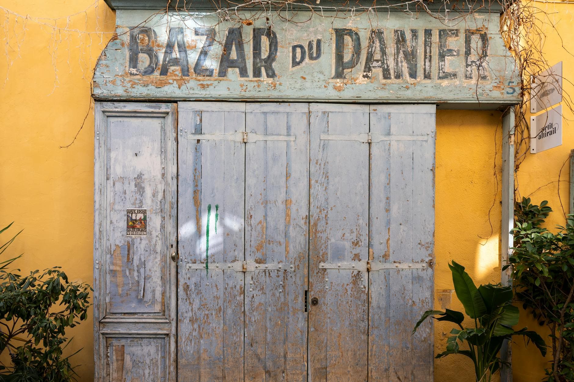 Rustic wooden door of the historic Bazar du Panier in a sunny French street.
