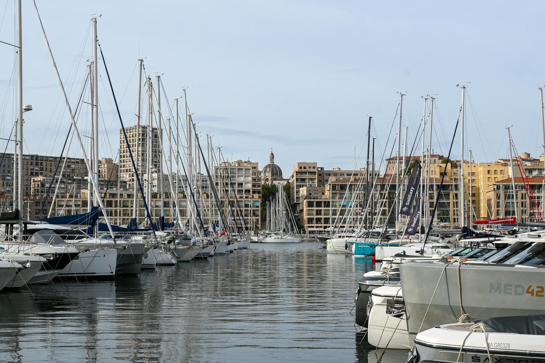 Stunning view of sailboats docked at the Old Port of Marseille with cityscape backdrop.
