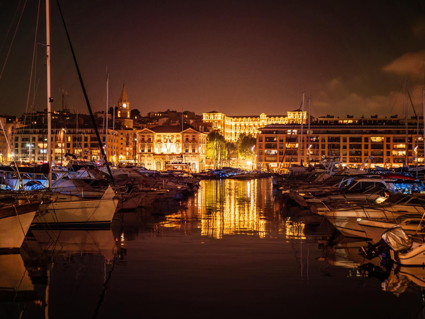 Beautiful view of a marina with yachts under night lights in Marseille, France.